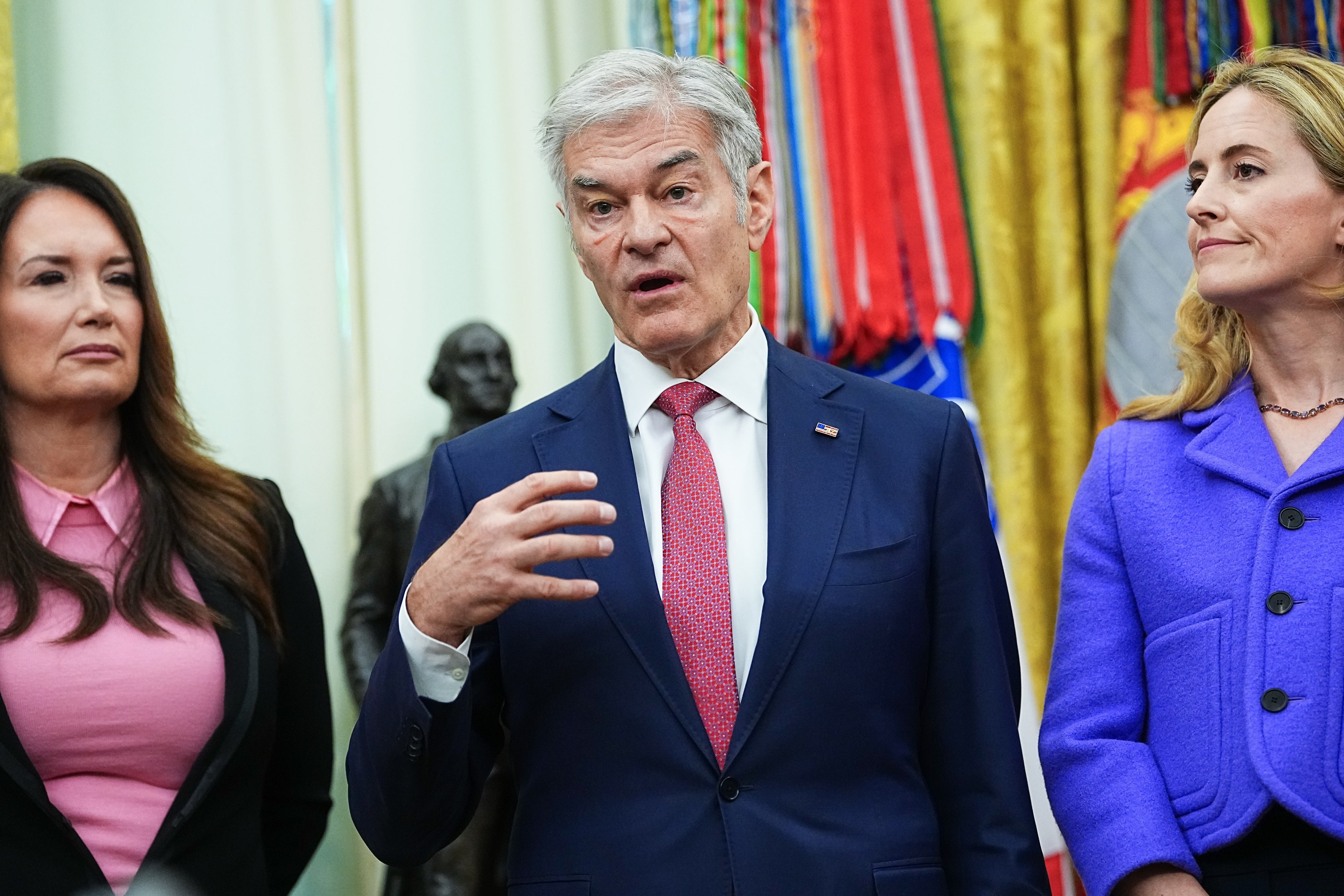 A radical  of 3  individuals stands successful  a ceremonial  setting. The cardinal  idiosyncratic   is gesturing portion    speaking, wearing a suit   and tie