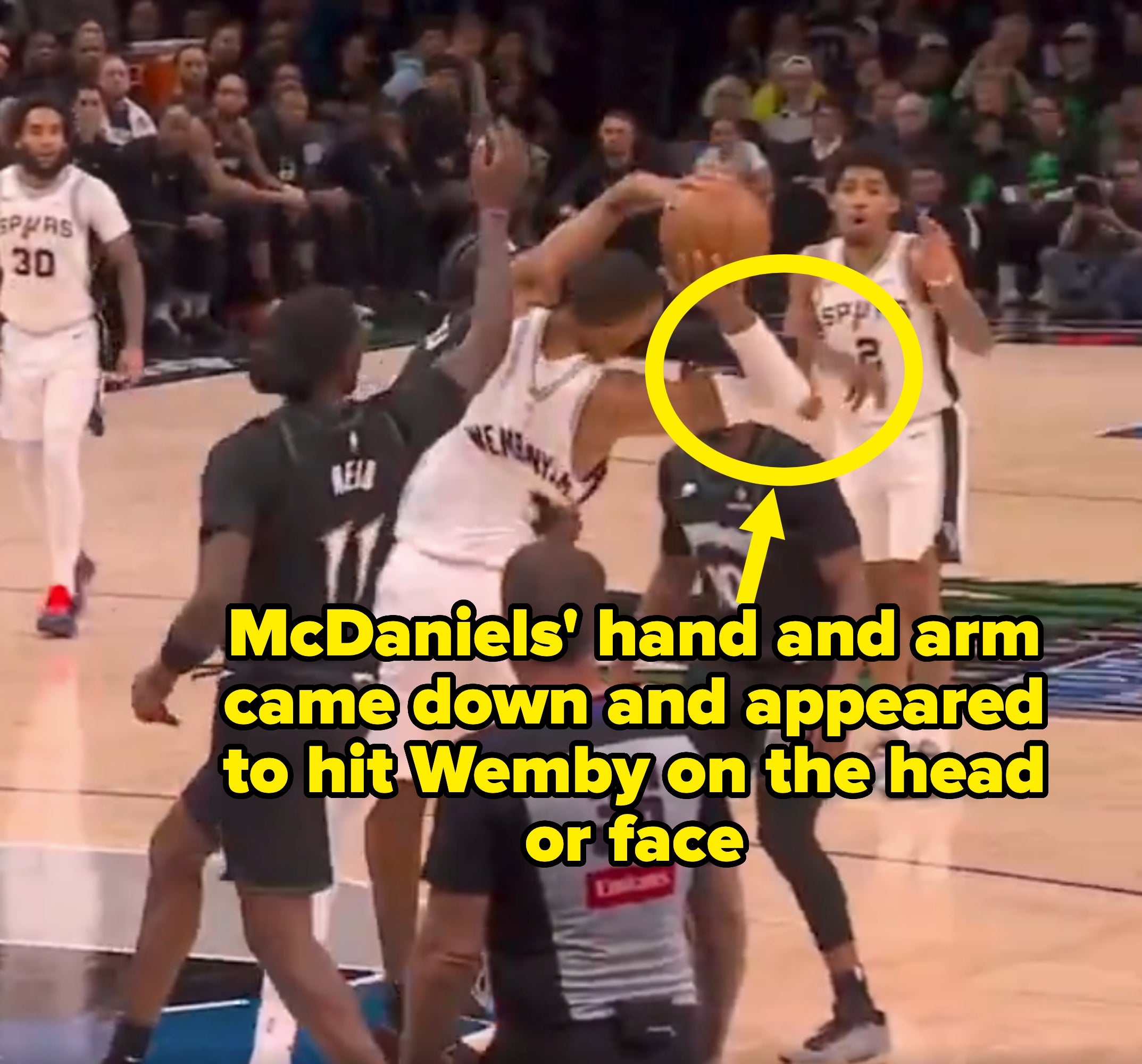 Basketball players from opposing teams vie  for possession during a crippled  connected  the court. An authoritative  observes successful  the foreground