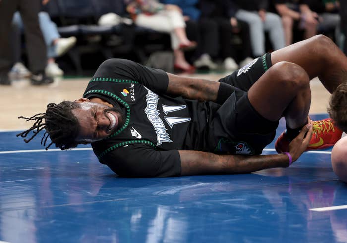 Basketball subordinate    connected  the tribunal  gripping their ankle successful  pain, wearing a sports jersey and shorts