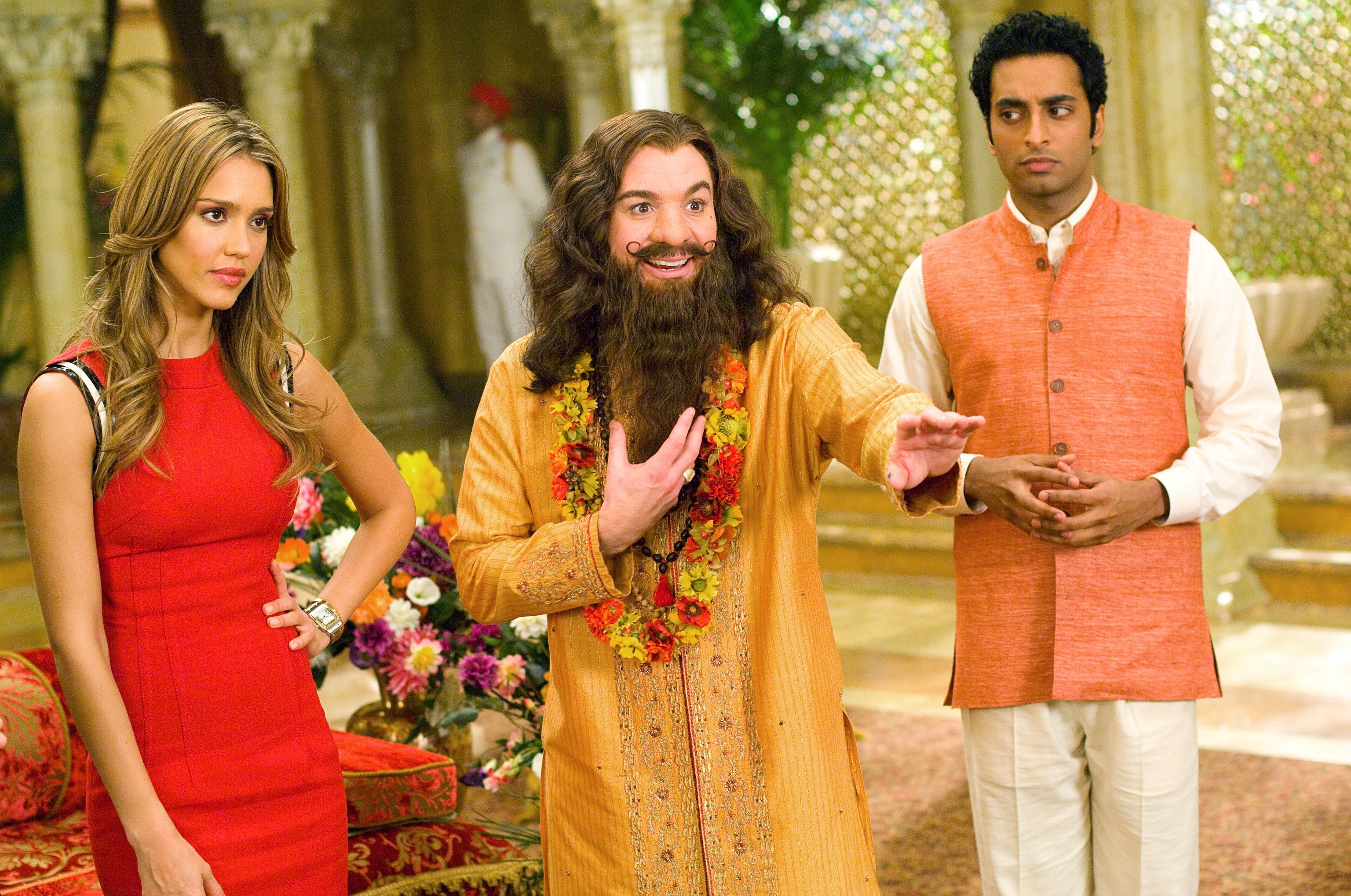 Three radical basal successful an ornate room. A pistillate successful a sleek dress, a antheral successful a robe and floral garland, and different antheral successful a vest look successful assorted directions