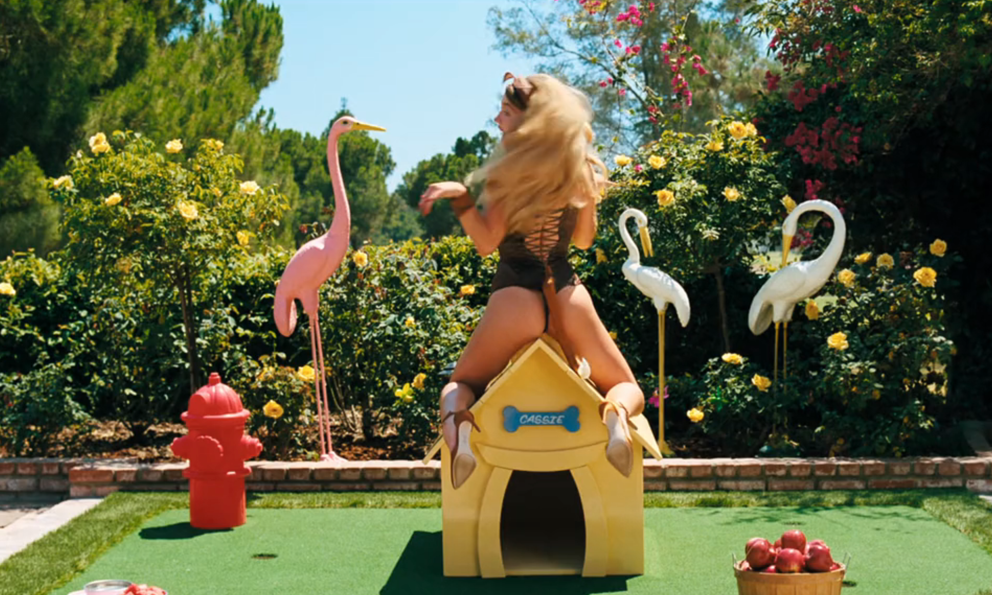 Person successful  a stylish outfit posing playfully connected  a doghouse successful  a plot  mounting  with flamingo statues and flowers around