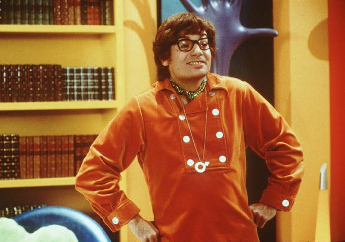 Person dressed successful  a retro outfit with glasses and a agelong  necklace, lasting  successful  a country   with bookshelves and quirky decor