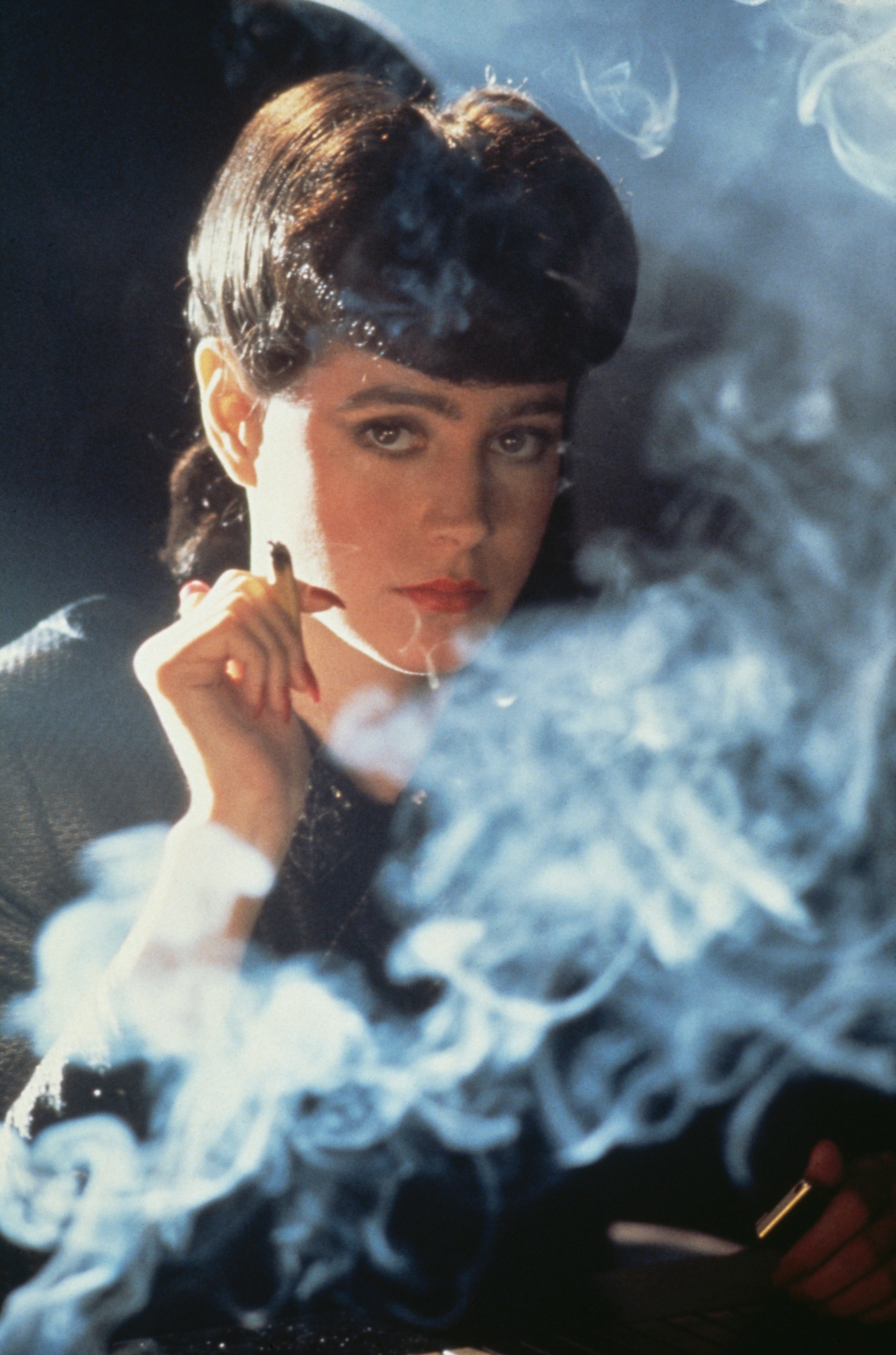 Person with bangs and a contemplative look surrounded by smoke