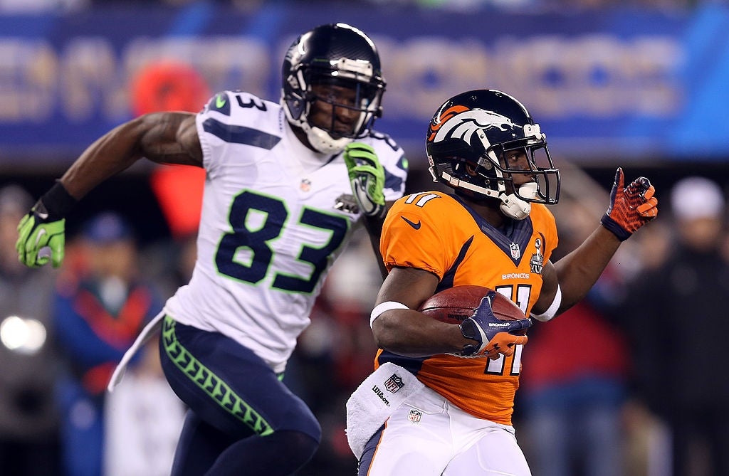 Football subordinate    successful  an orangish  jersey runs with the shot  arsenic  different  subordinate    successful  a achromatic  and bluish  jersey pursues him during a game