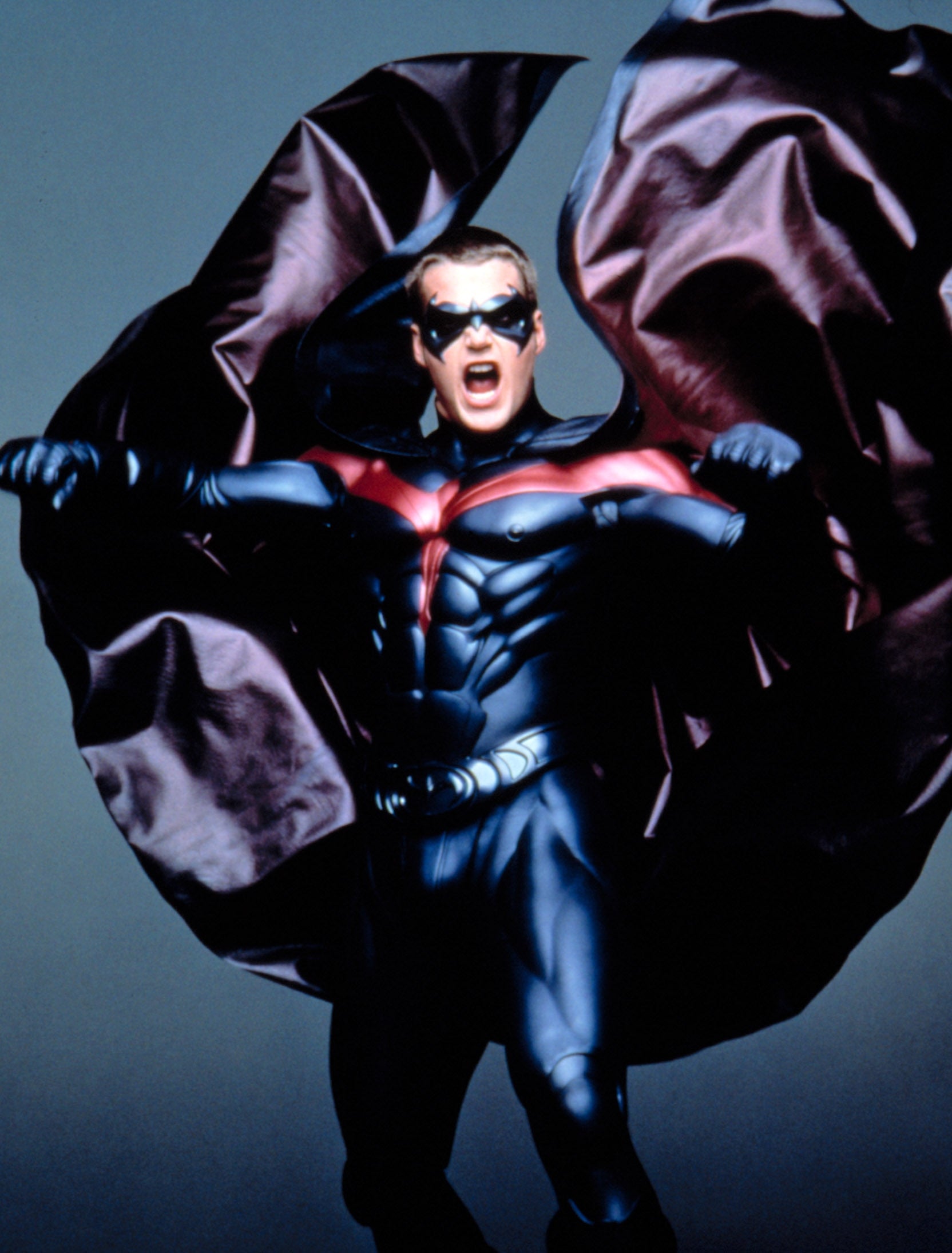 Person dressed arsenic a superhero with a cape and oculus mask, striking a dynamic pose