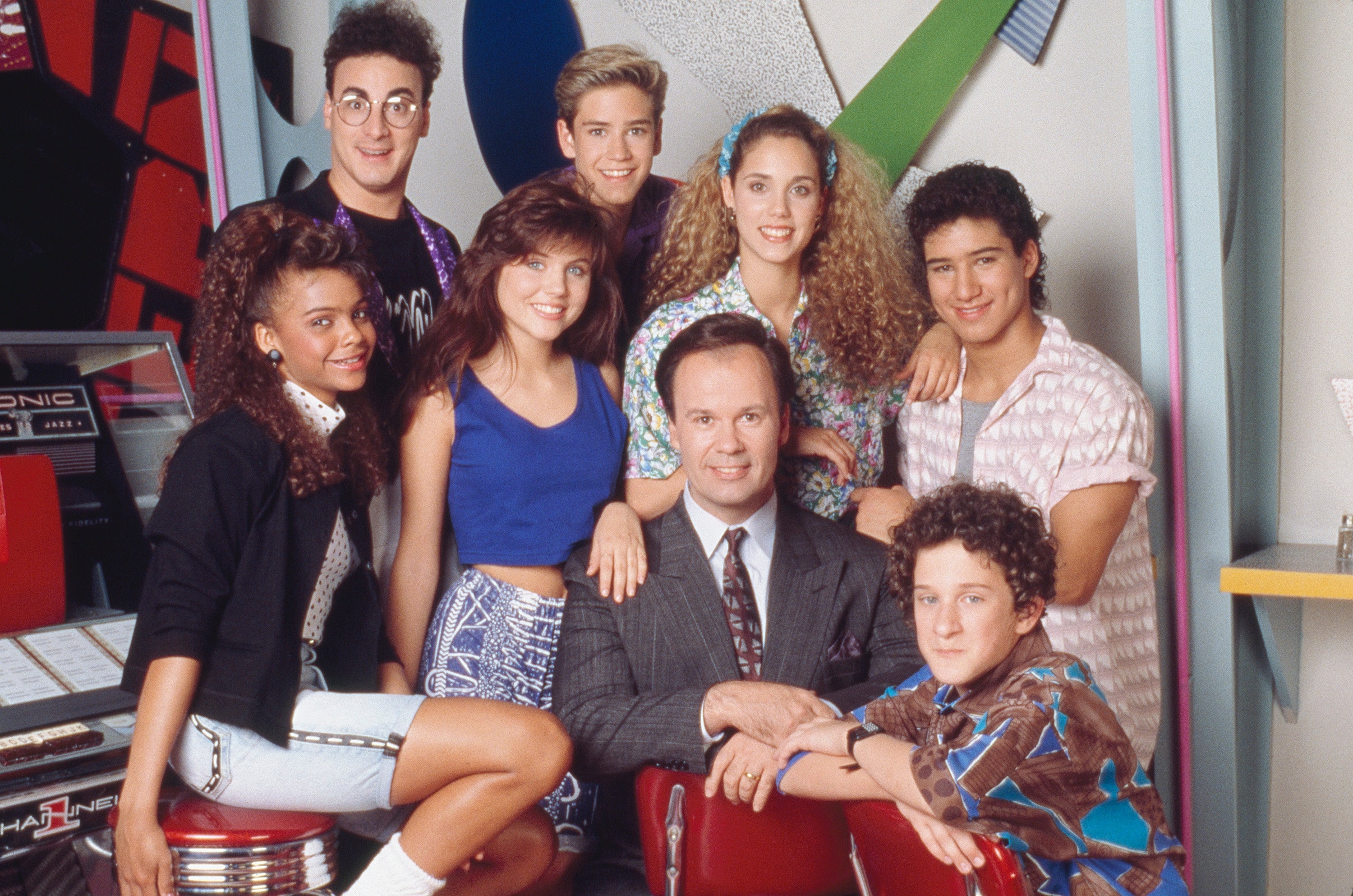 A radical of young adults and a suited antheral airs together, showcasing 90s manner styles with vibrant patterns and casual attire
