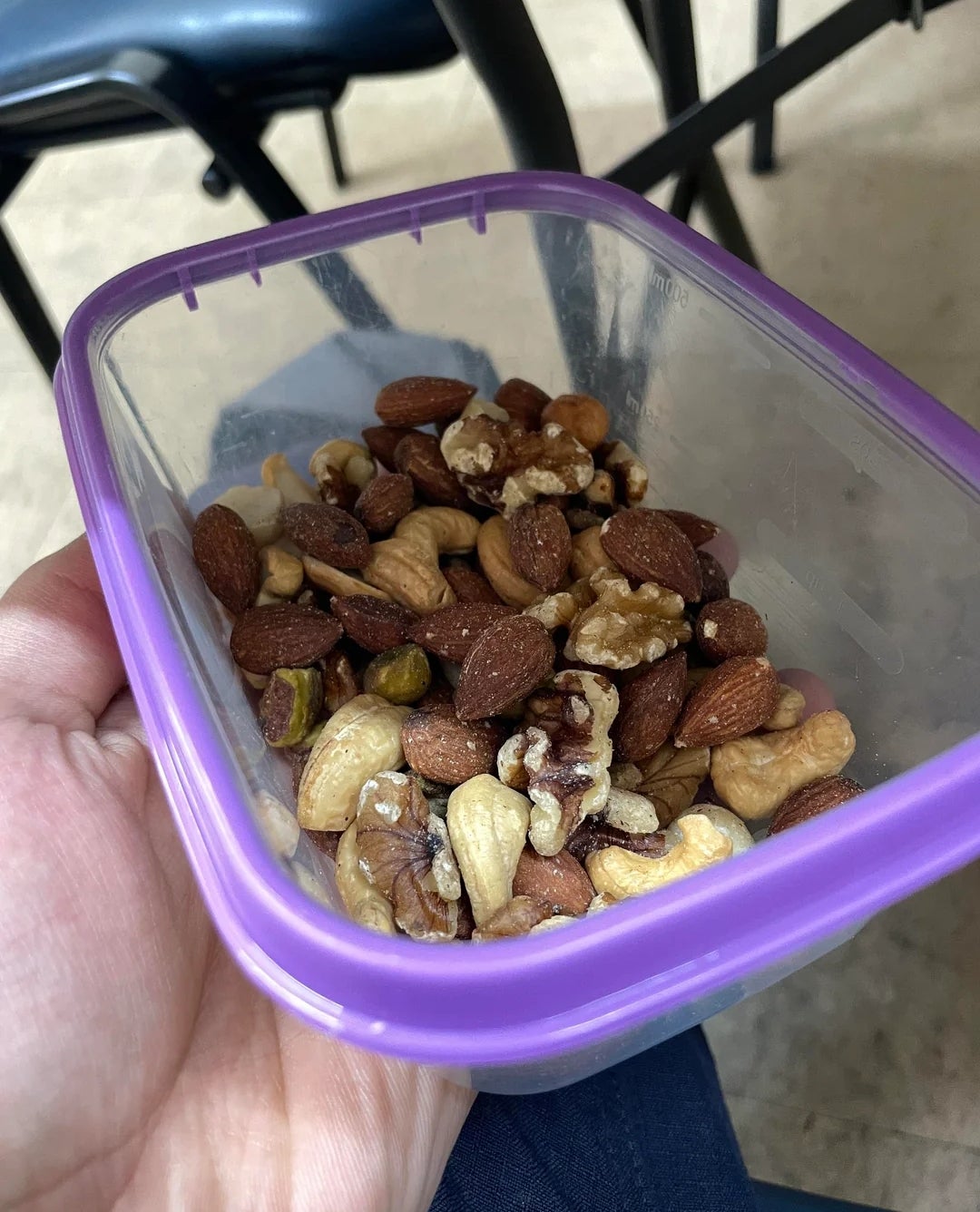 Mixed nuts including almonds, cashews, walnuts, and pistachios in a clear plastic container