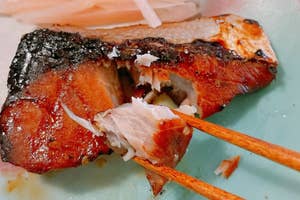 焼き魚が箸でほぐされた状態で皿に盛られ、大根のつまが添えられているシーン。