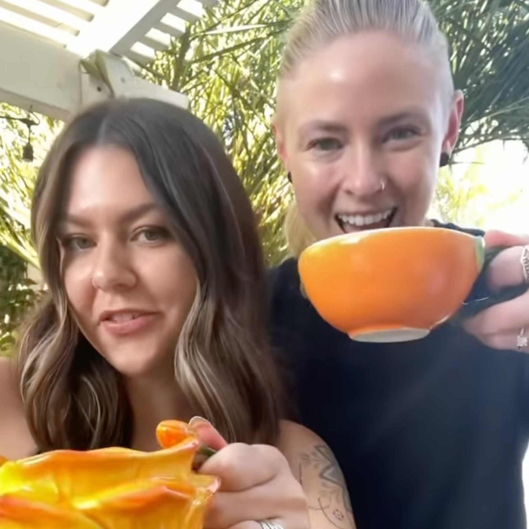 2人の女性が大きな花の形のカップで飲み物を楽しんでいる。楽しい表情。