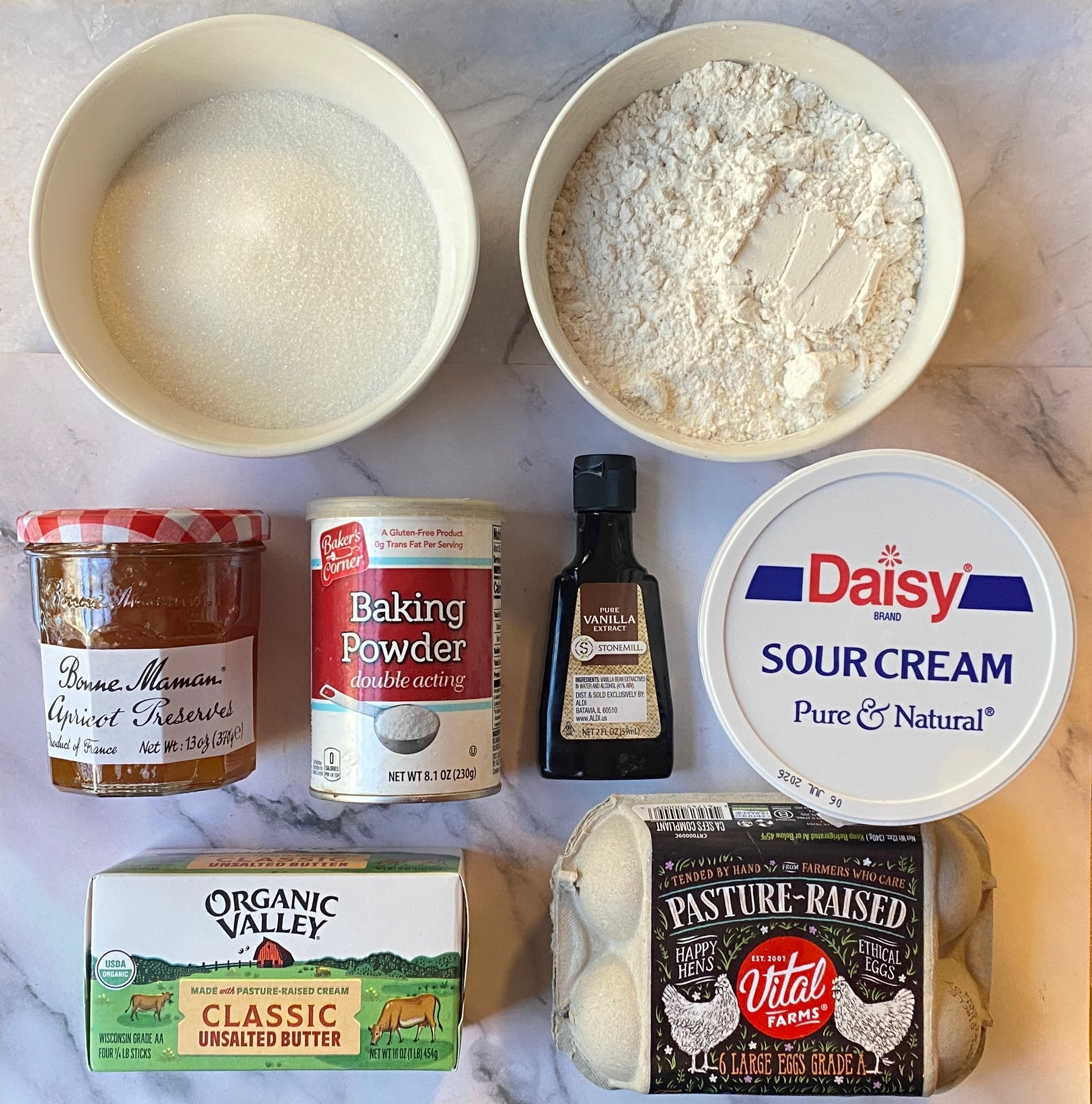 Ingredients for baking: apricot preserves, baking powder, vanilla extract, sour cream, butter, eggs, and flour