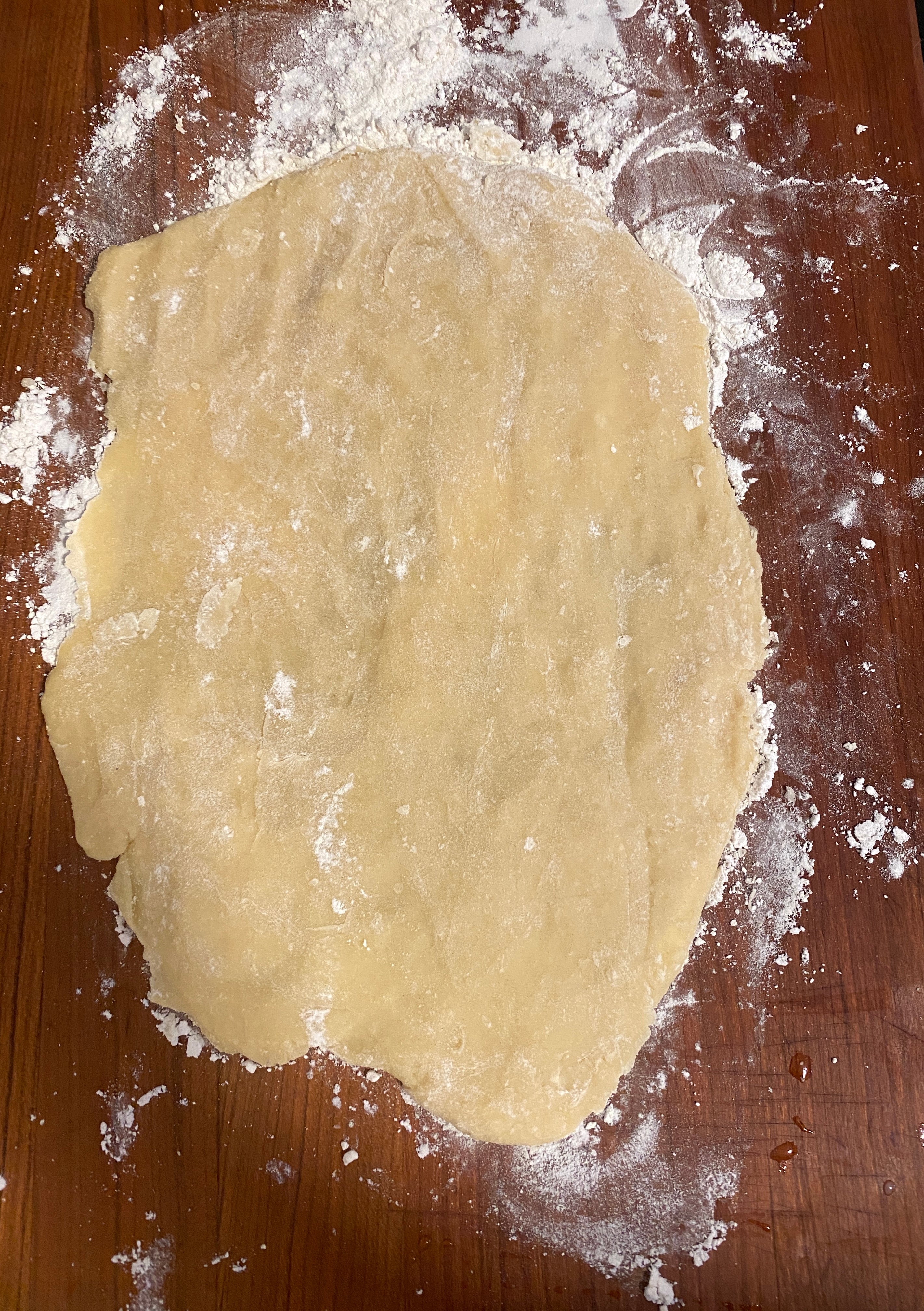 Rolled out dough on a floured wooden surface, ready for baking or cooking preparation