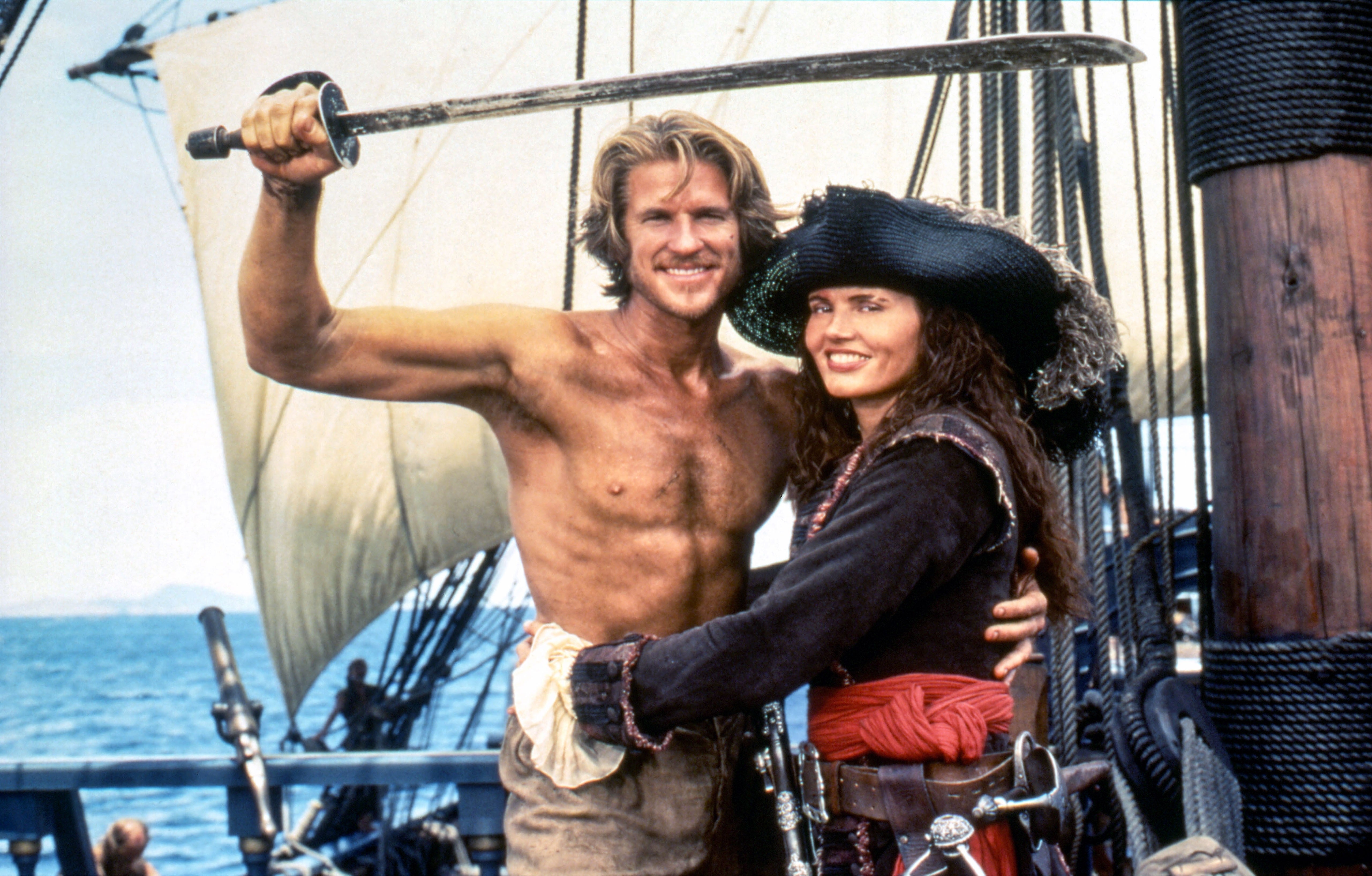 A shirtless antheral holds a sword portion lasting adjacent to a pistillate successful pirate attire connected a ship's deck