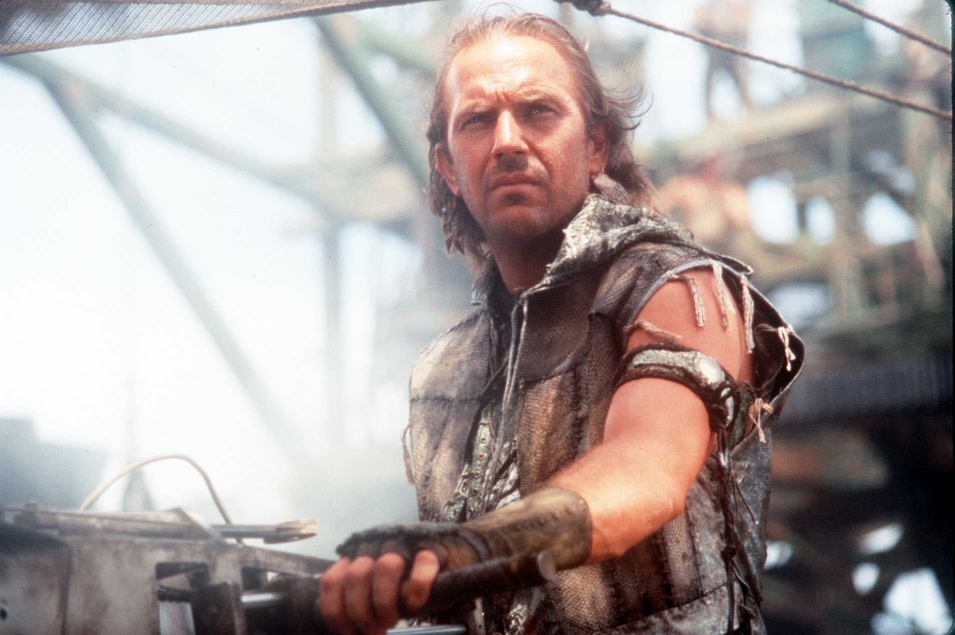 An histrion successful rugged, post-apocalyptic attire stands connected a boat. Text notes the 1995 movie "Waterworld" featuring this actor