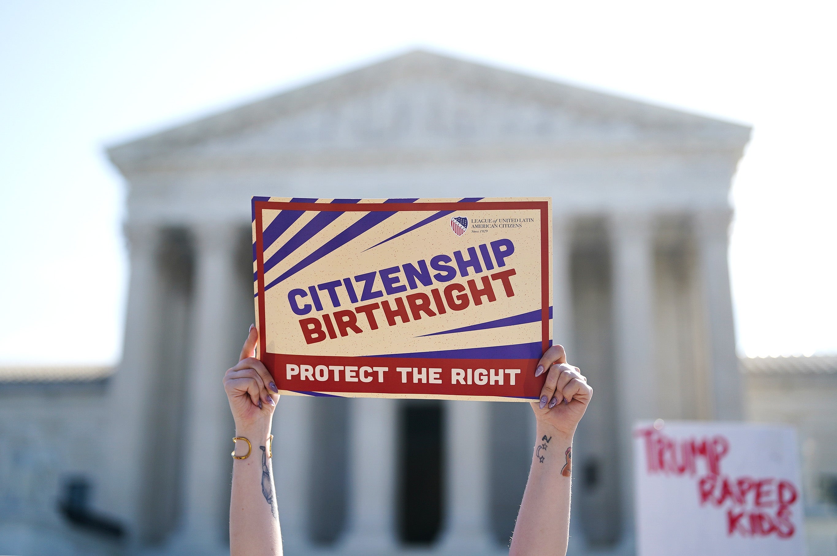 Demonstranten innehar "Citizenship Birthright: Protect the Right" skilt utenfor en stor, klassisk regjeringsbygning