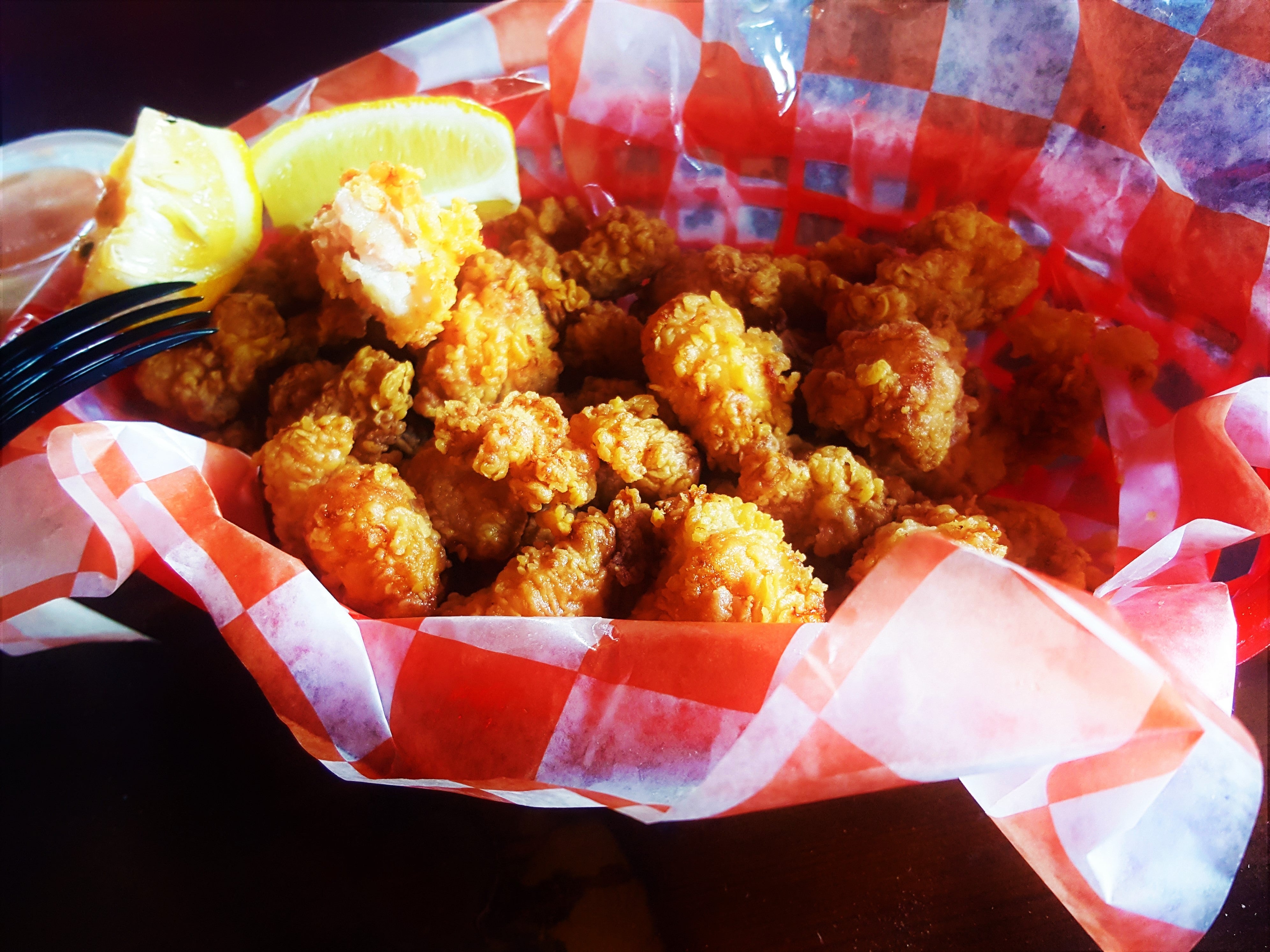 Basket of fried alligator with a lemon wedge and a dipping sauce on the side