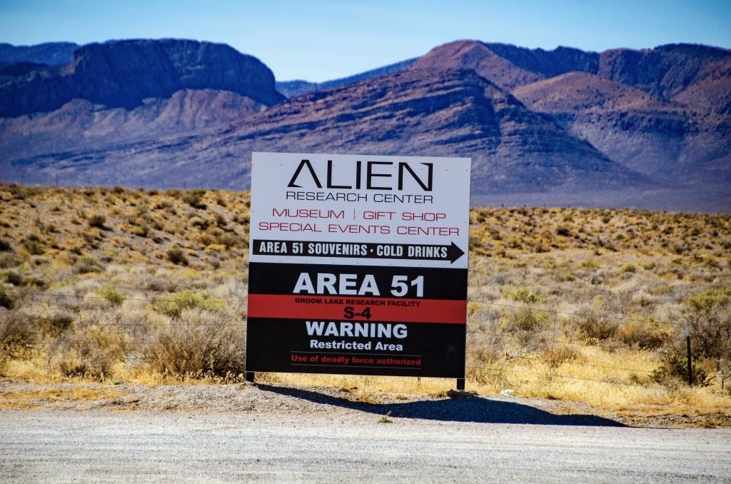 Skilt til Alien Research Center nær fjell, nevner område 51-gaver og en advarsel for et begrenset område med kun autorisert personell