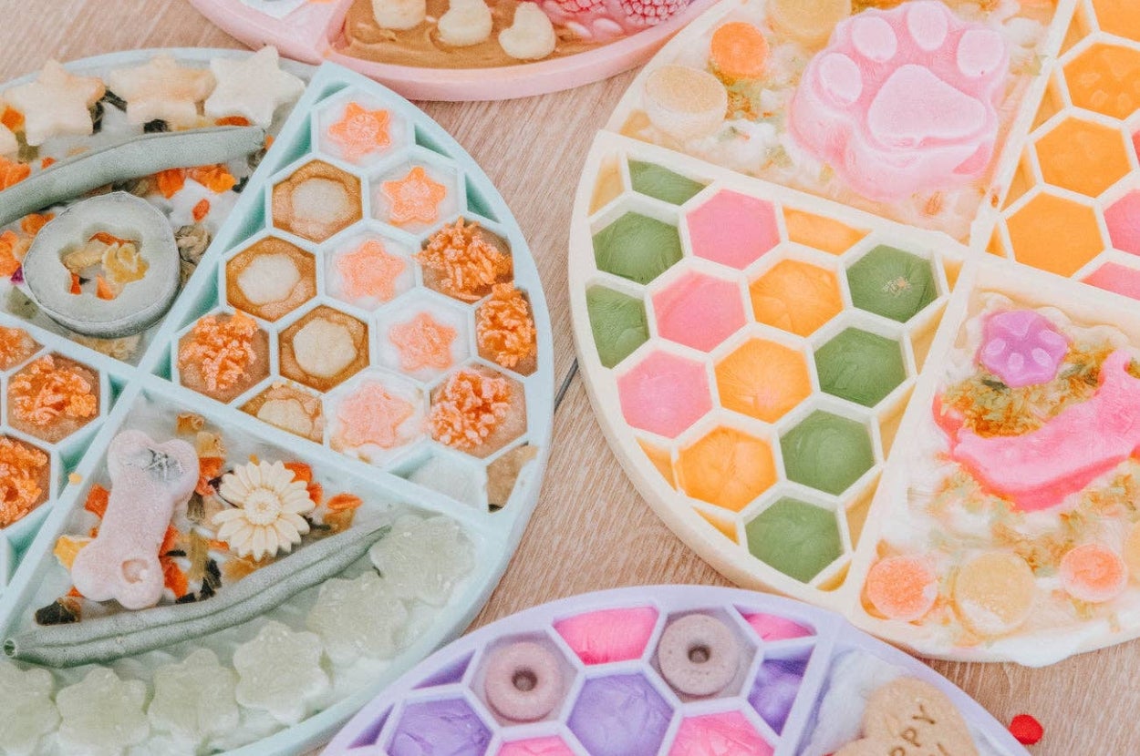 Assorted colorful silicone molds filled with various decorative and playful soap shapes, including flowers and animals, ideal for gifting