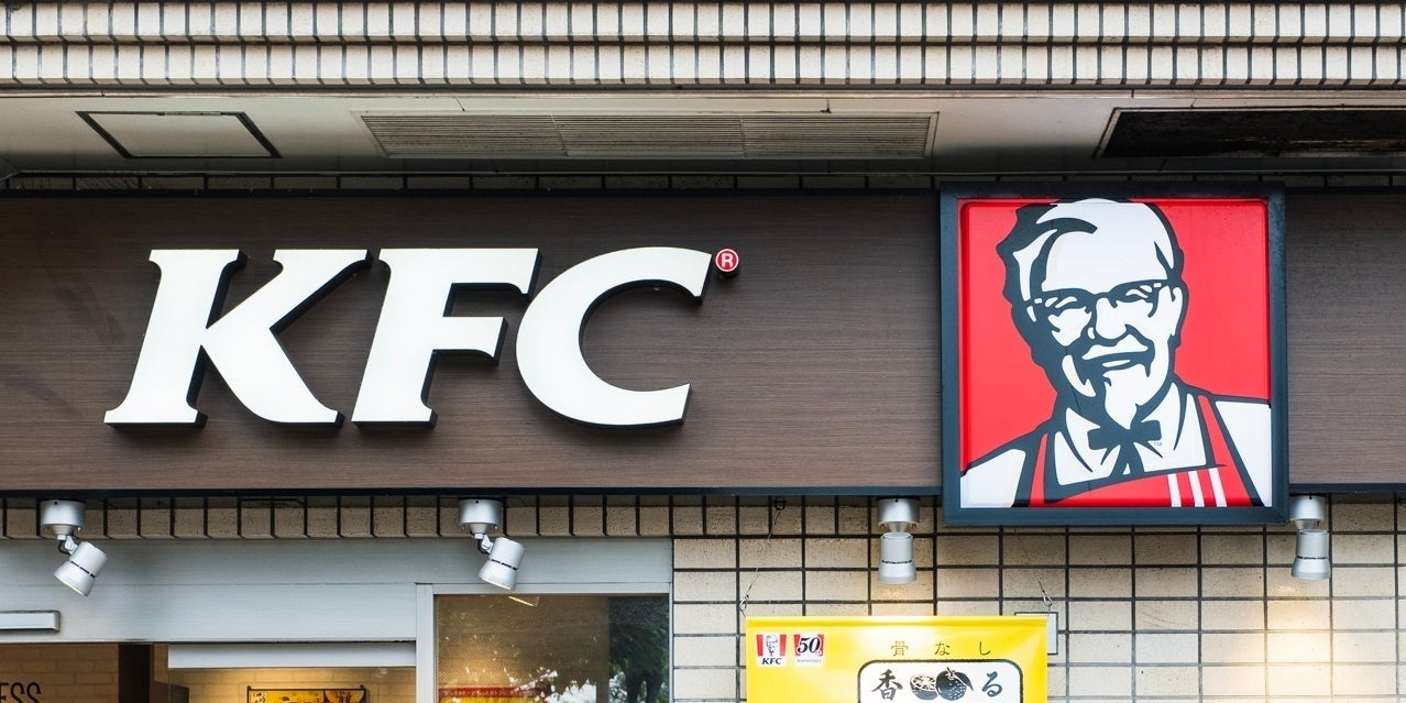 KFCの店舗の看板。左に大きな「KFC」の文字、右にカーネル・サンダースのイラストが描かれた看板があります。