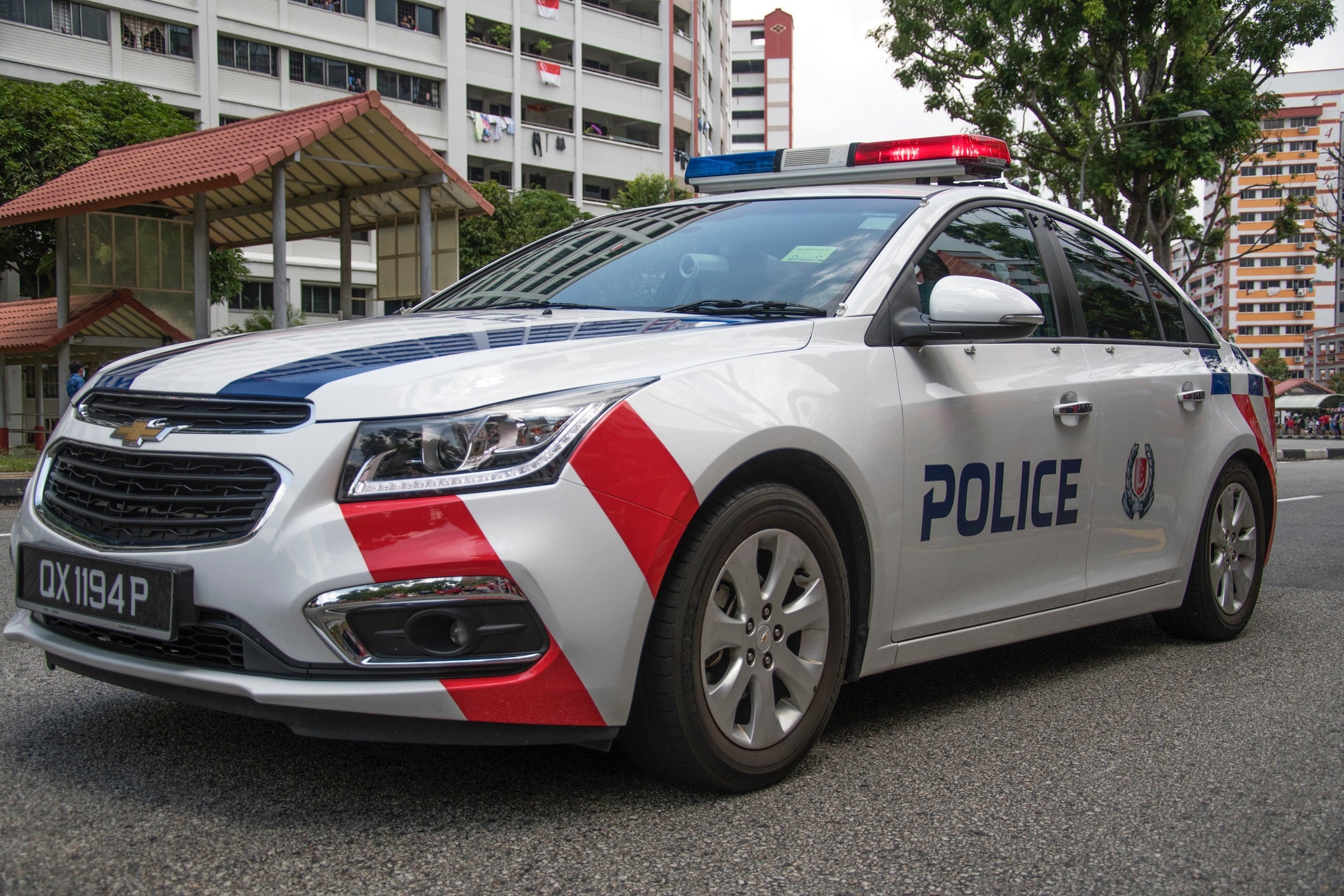 Police car parked on a city street near buildings and trees