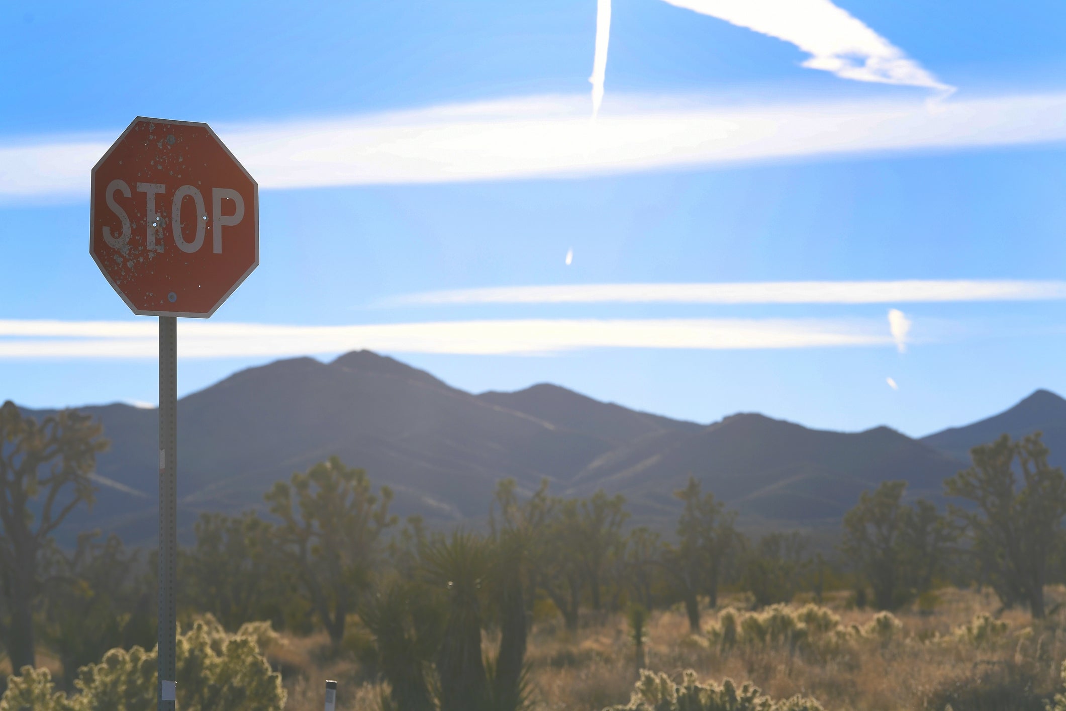 Stop sign in a desert landscape with mountains and a clear sky in the background