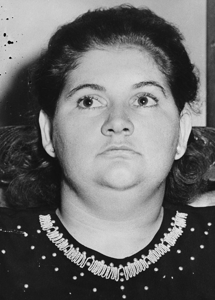 A person with a serious expression, wearing a decorative collar. The photograph appears to be candid or historical