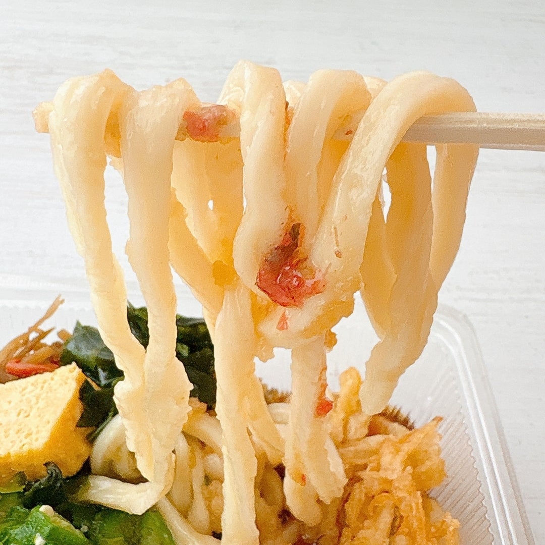 丸亀製麺の「梅おろしオクラうどん弁当」のうどんを箸で持ち上げている様子。