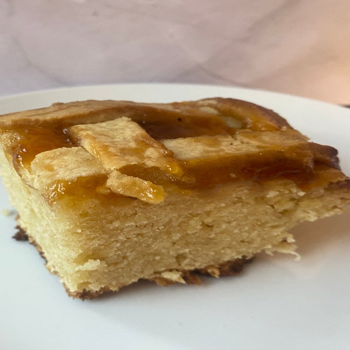A slice of moist cake with a lattice crust topping on a white plate