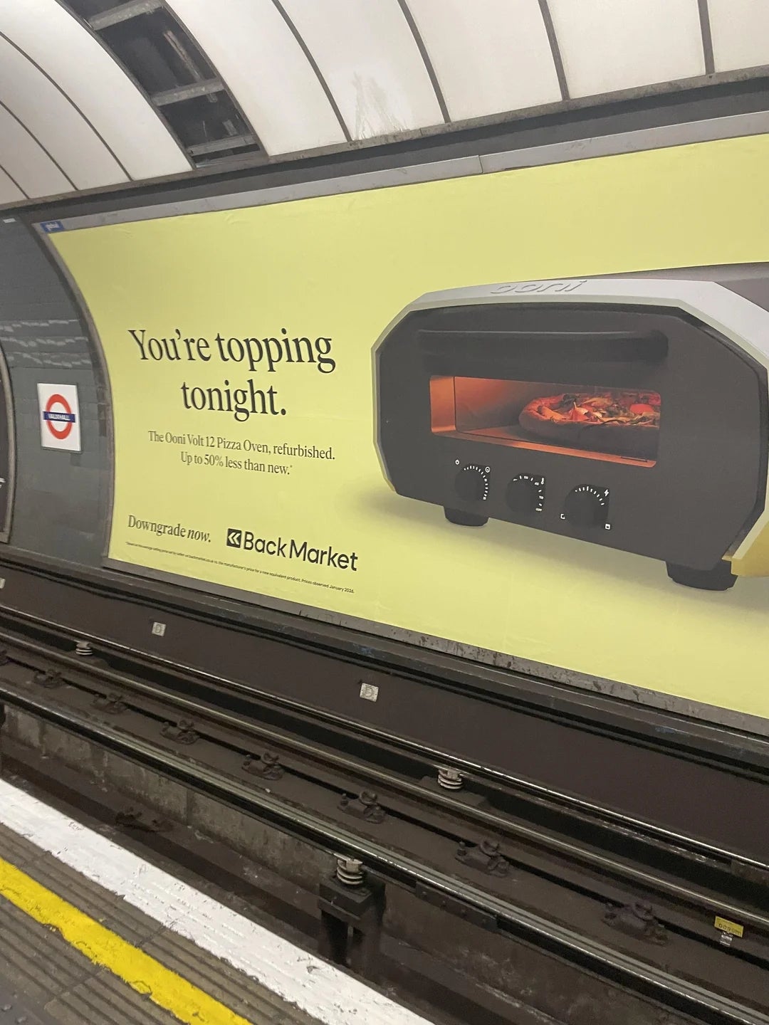 Billboard successful  a subway presumption    advertizing  a pizza oven with a connection   astir  topping pizzas and utilizing refurbished products