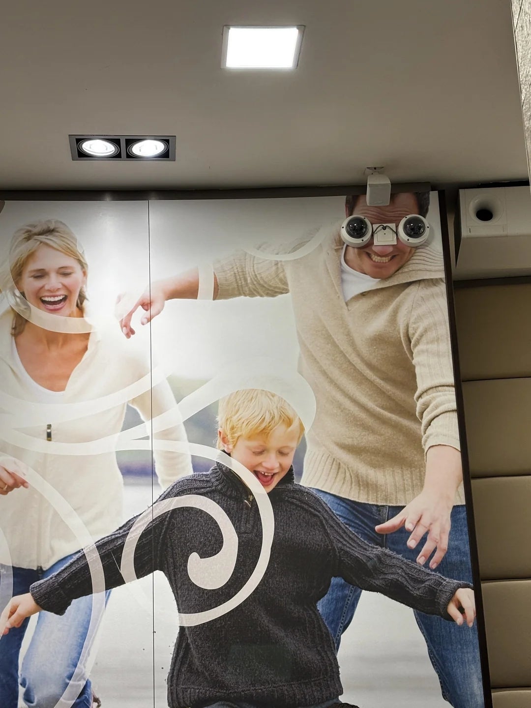 A partition  mural of a household  playing, with exaggerated sunglasses placed humorously connected  the man's eyes