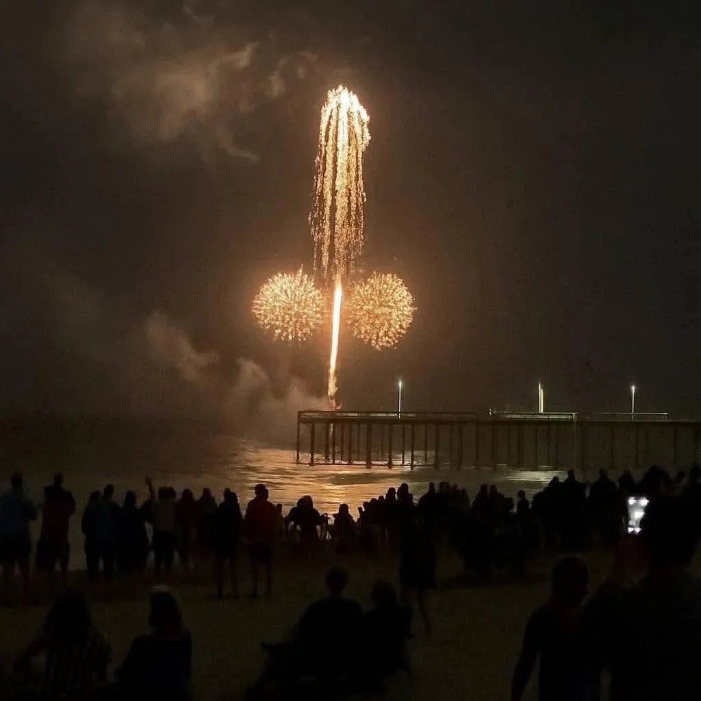 Fireworks show  implicit    a pier astatine  night, with a assemblage  watching connected  the beach