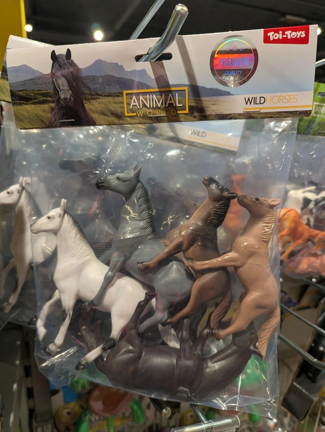 Package of artifact  horses labeled "Wild Horses" from the marque  Animal World, hanging connected  a store   display