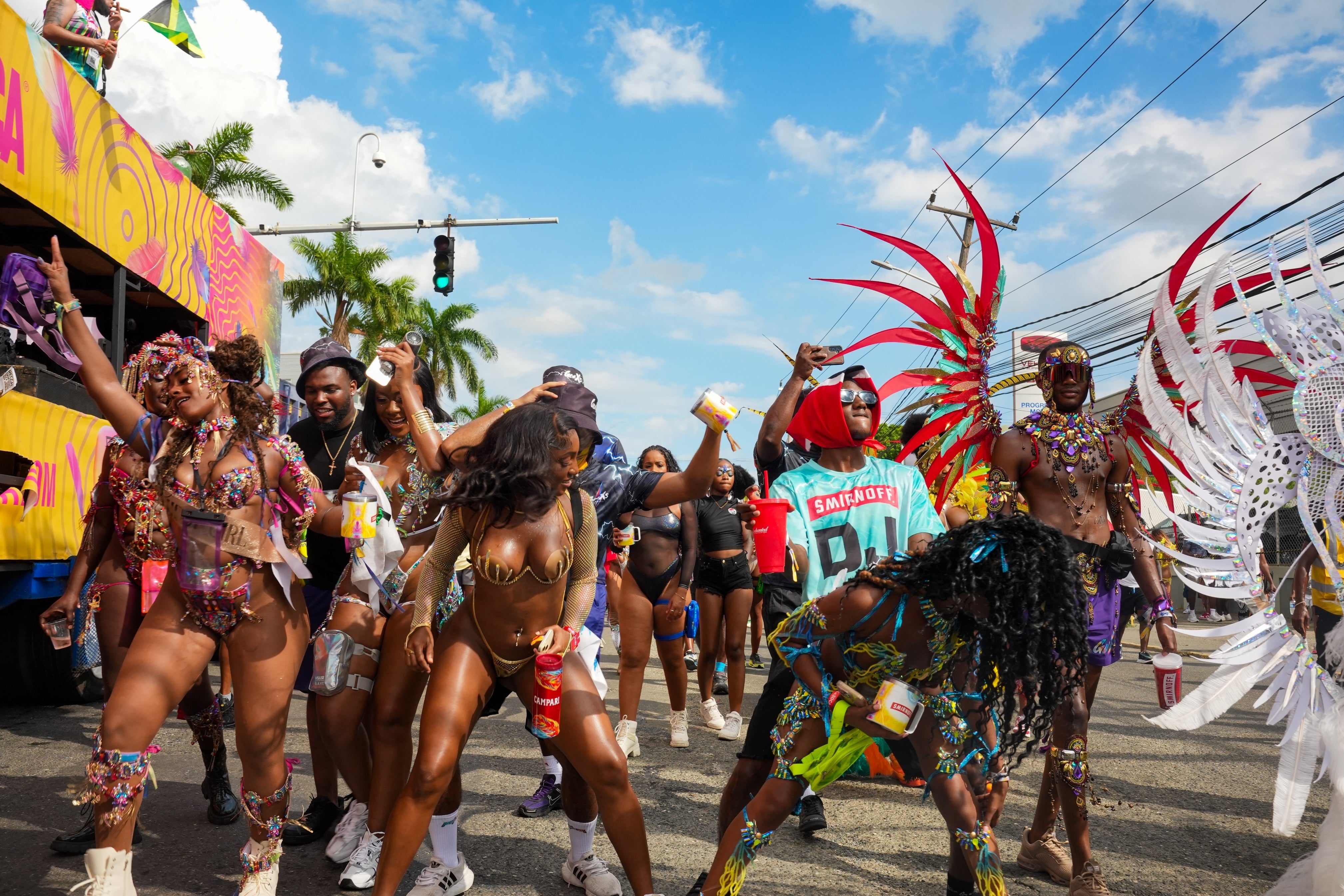 People in vibrant carnival costumes dance energetically in the street during a festive parade
