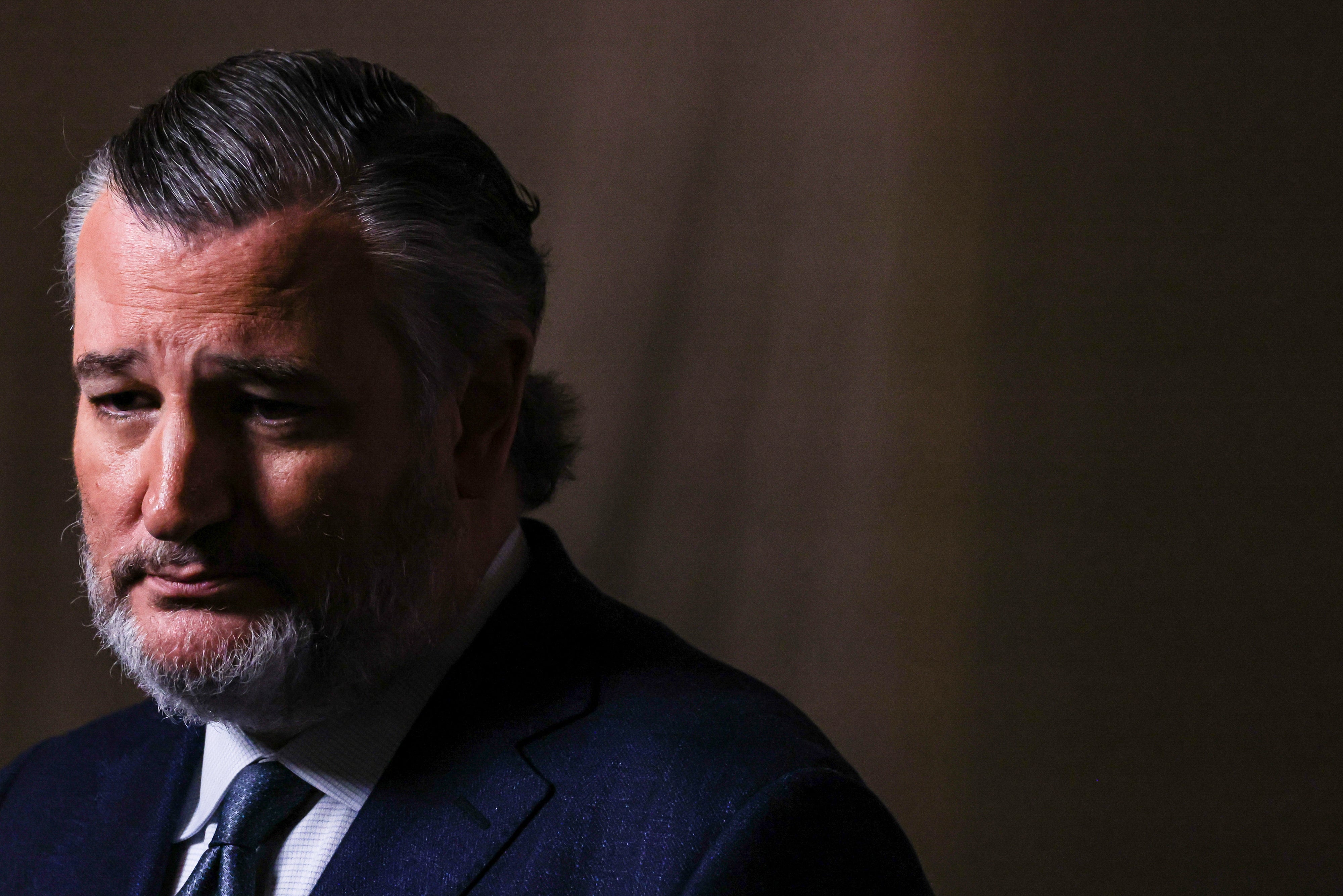 Person successful a suit, facing near with a thoughtful expression, against a acheronian background