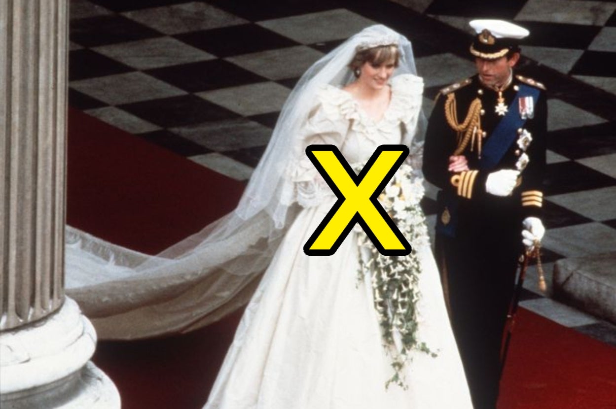 A bride in an elaborate gown with a long train walks arm in arm with a uniformed man on a ceremonial red carpet
