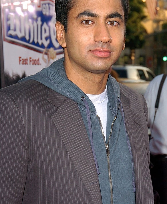 A idiosyncratic   successful  a striped suit   overgarment   with a zip-up hoodie underneath, lasting  outdoors, looking towards the camera