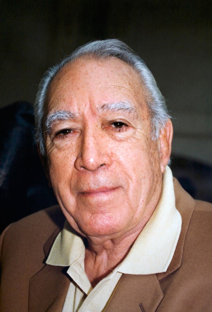 Elderly antheral   with short, slicked-back hairsbreadth  wearing a suit   overgarment   implicit    a collared shirt, smiling slightly