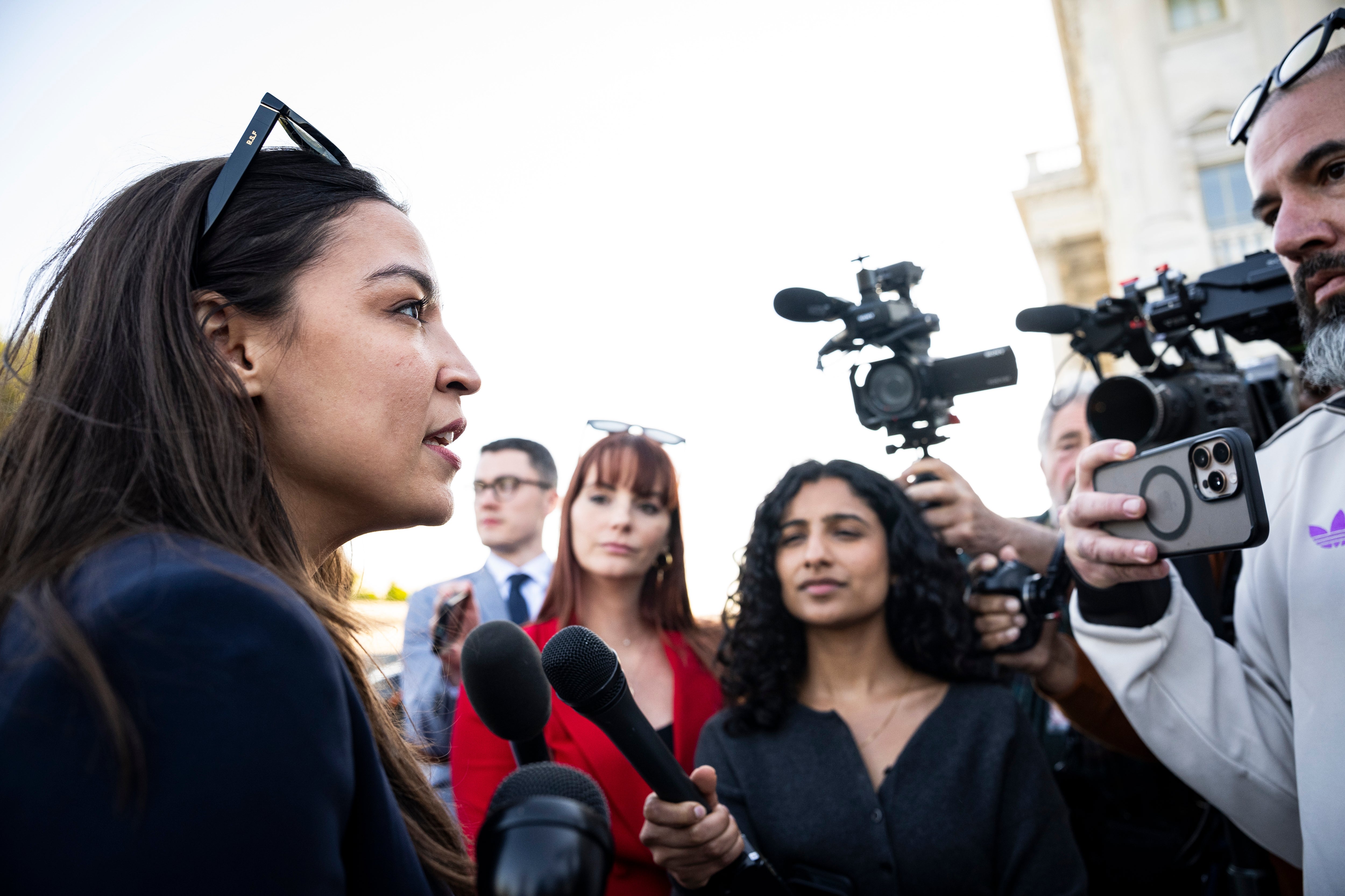 Person speaking to reporters with cameras and microphones gathered around