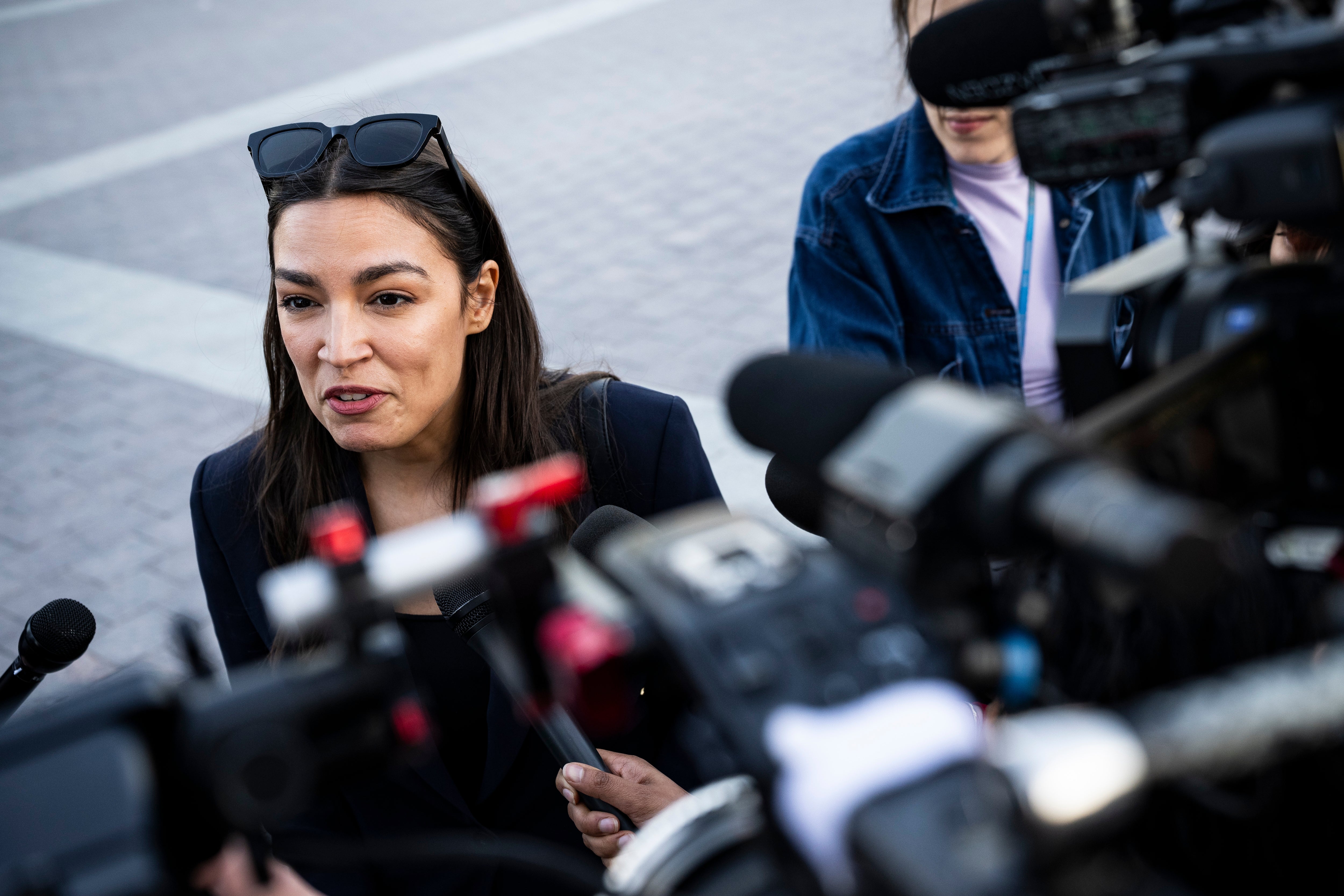 A idiosyncratic successful a concern suit speaks to a assemblage of journalists, surrounded by microphones and cameras