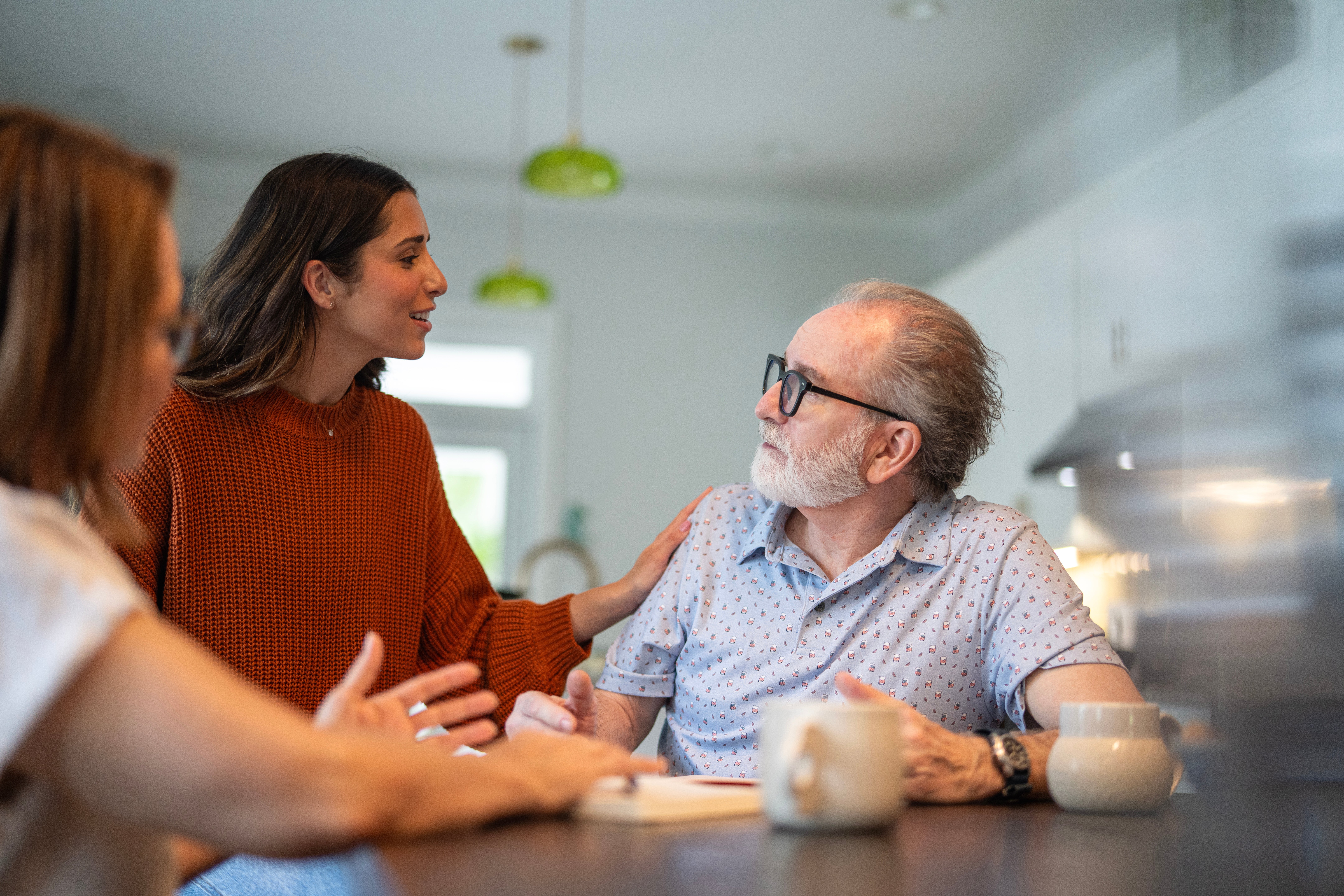 A pistillate   and 2  older adults beryllium   astatine  a table, engaged successful  a affable  conversation
