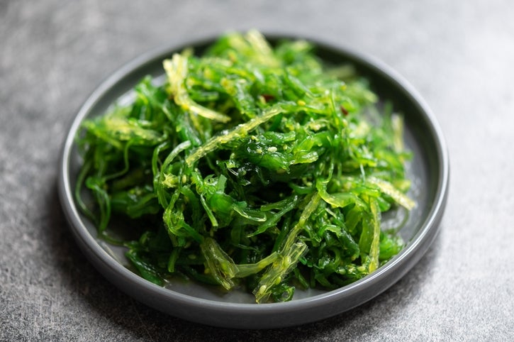 A close-up of a plate of fresh seaweed salad served on a dark round dish