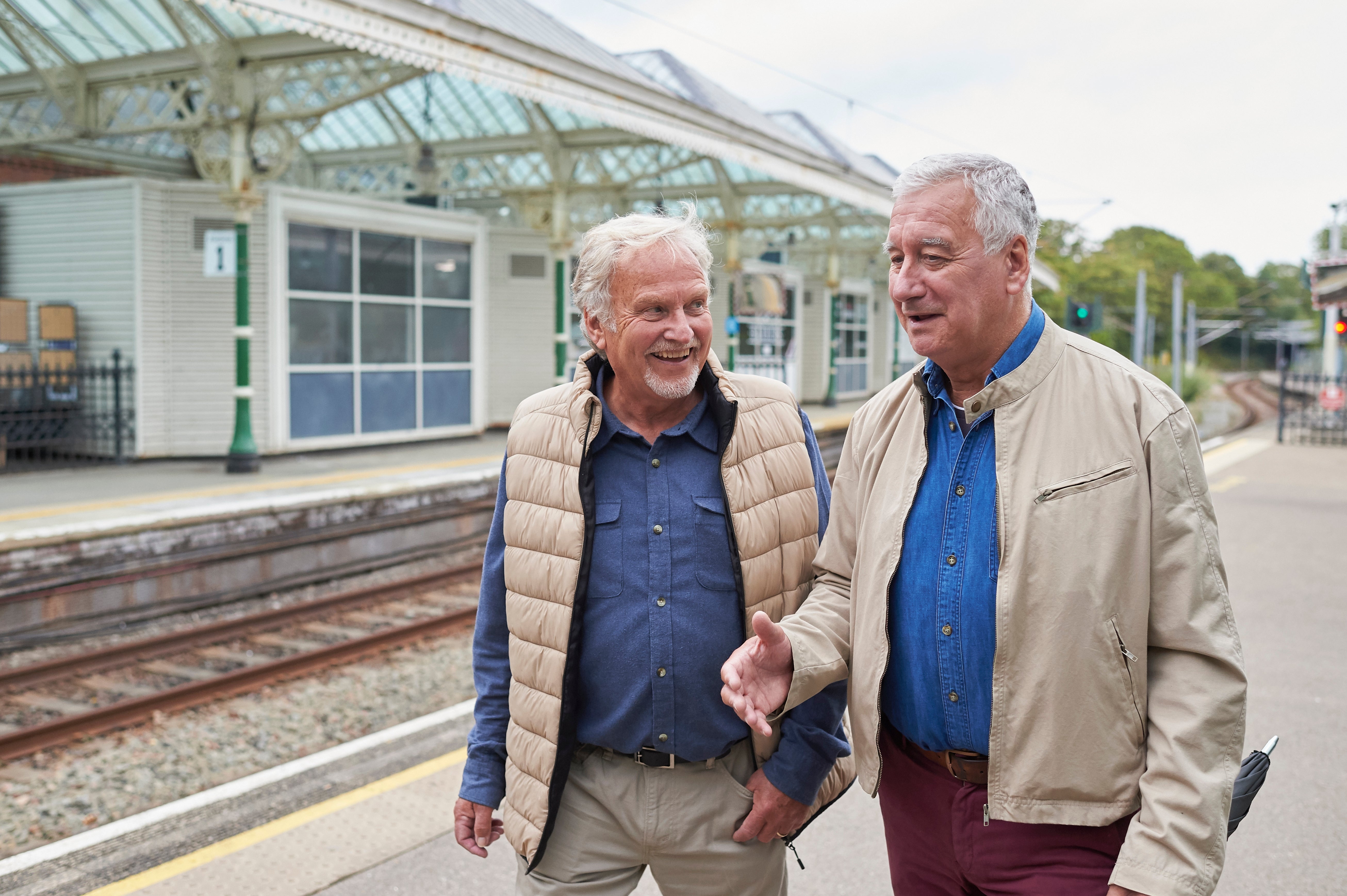 Two older adults walking and chatting connected  a bid     platform, some  wearing casual jackets