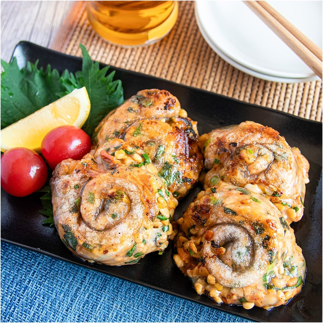 お皿に盛られた納豆のライスペーパー巻き、添えられたレモン、プチトマト、大葉。