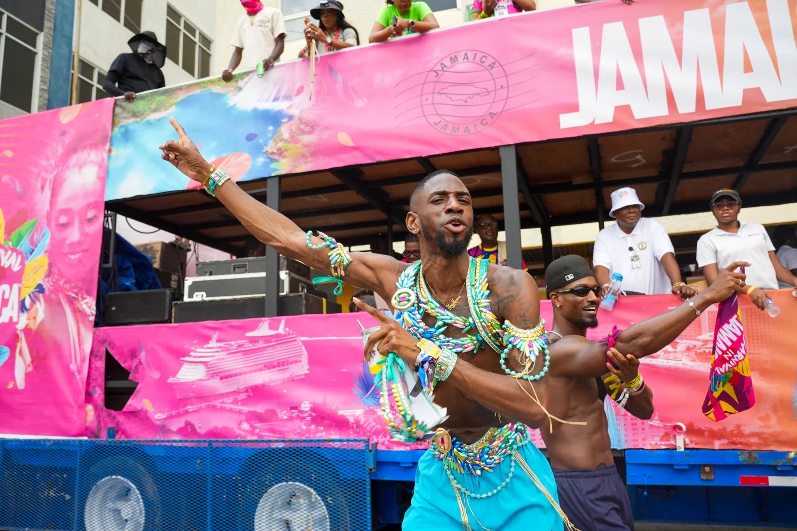 People dancing energetically on a parade float in Jamaica, adorned with vibrant costumes, during a lively festival celebration