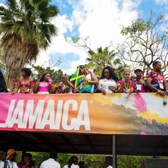 People celebrating at a festival in Jamaica, waving flags and dressed in vibrant outfits on a decorated float