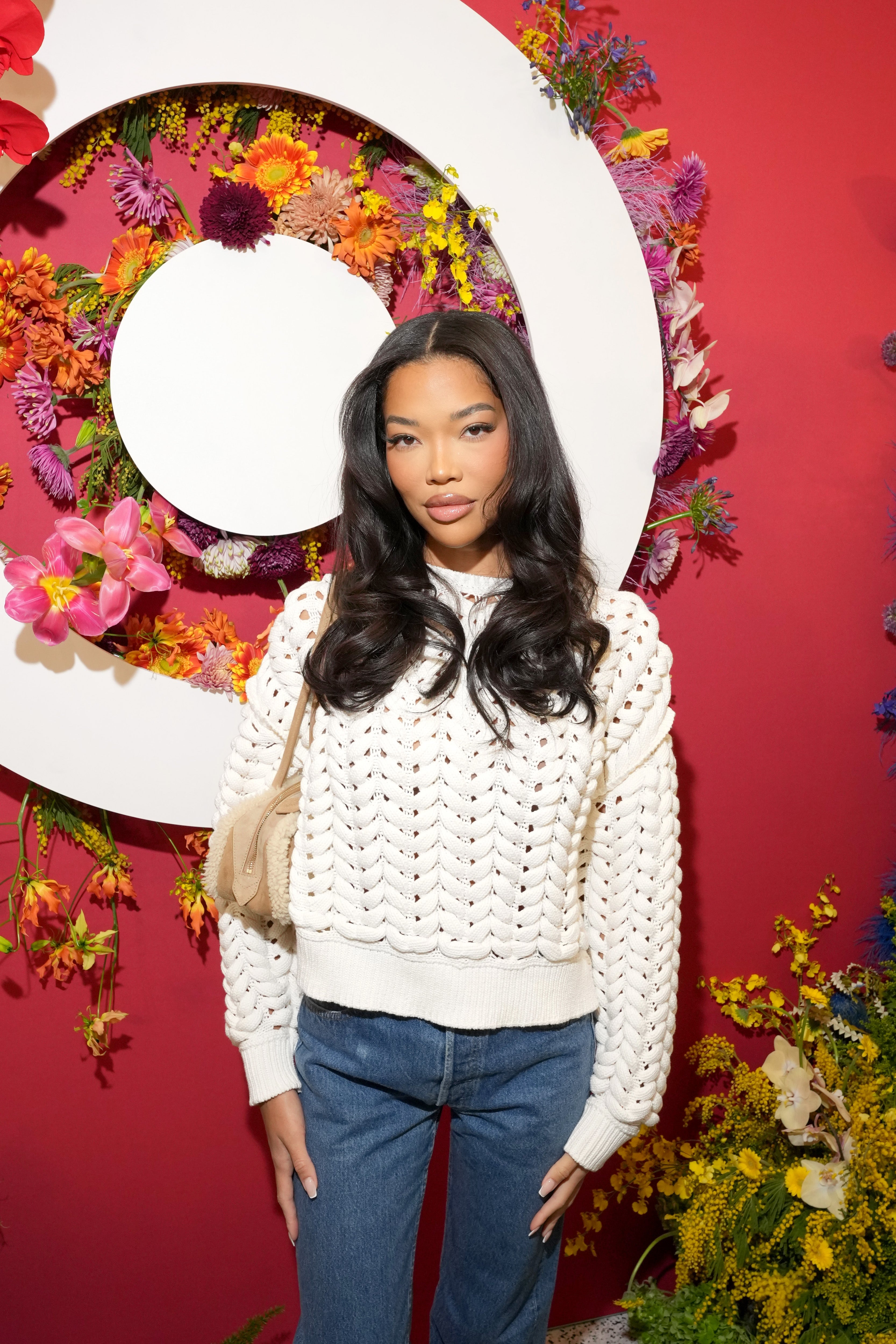 Person successful  a achromatic  knitted sweater and jeans stands successful  beforehand   of a floral backdrop