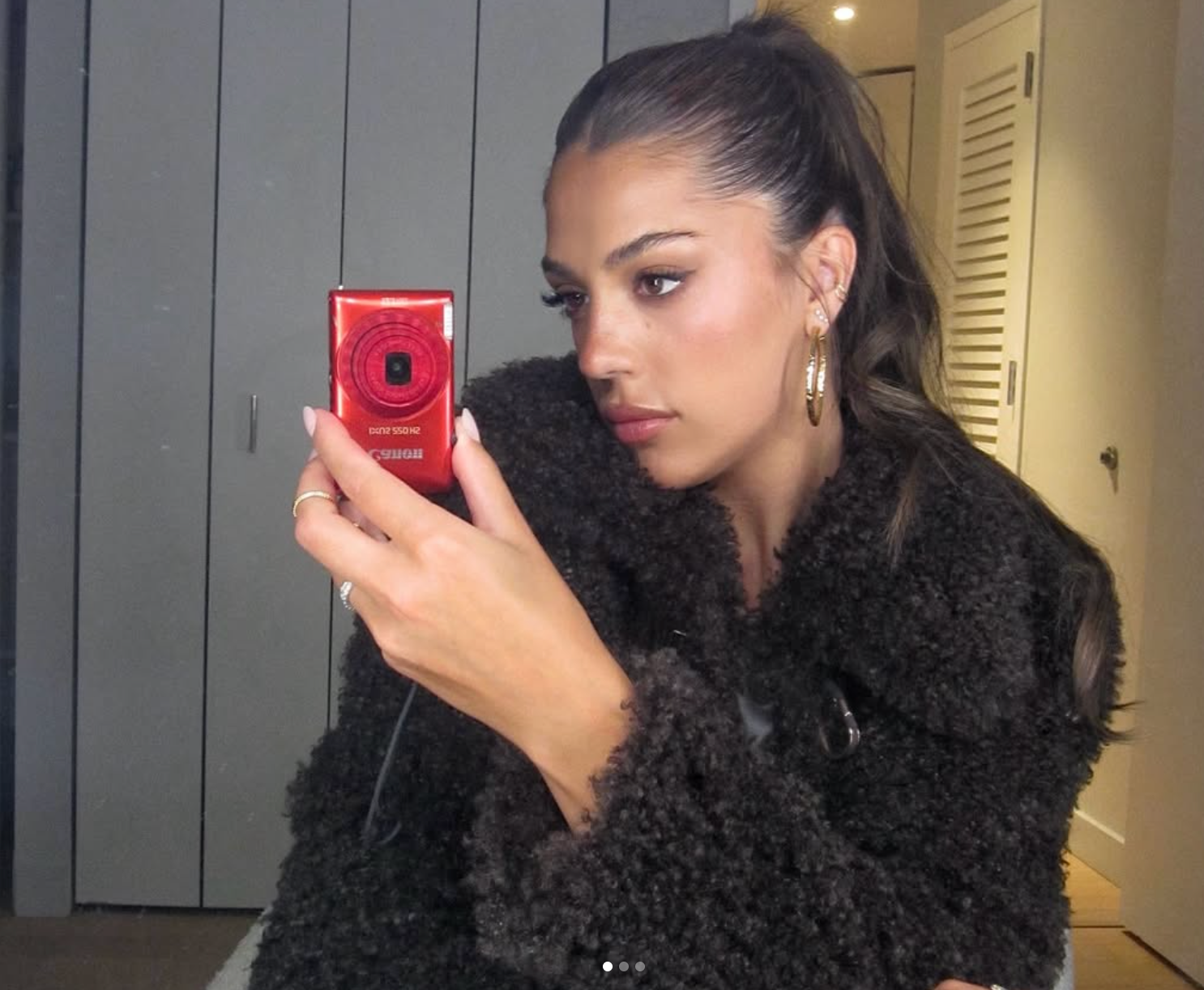 Person taking a reflector  selfie, wearing a fluffy textured overgarment  and hoop earrings, with hairsbreadth  successful  a ponytail
