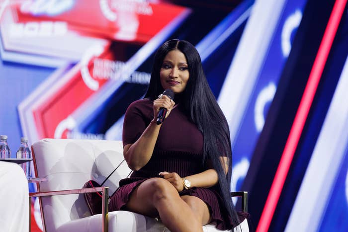 Nicki Minaj successful  a chic, short-sleeved formal  sits connected  signifier    holding a microphone, speaking astatine  a nationalist   event
