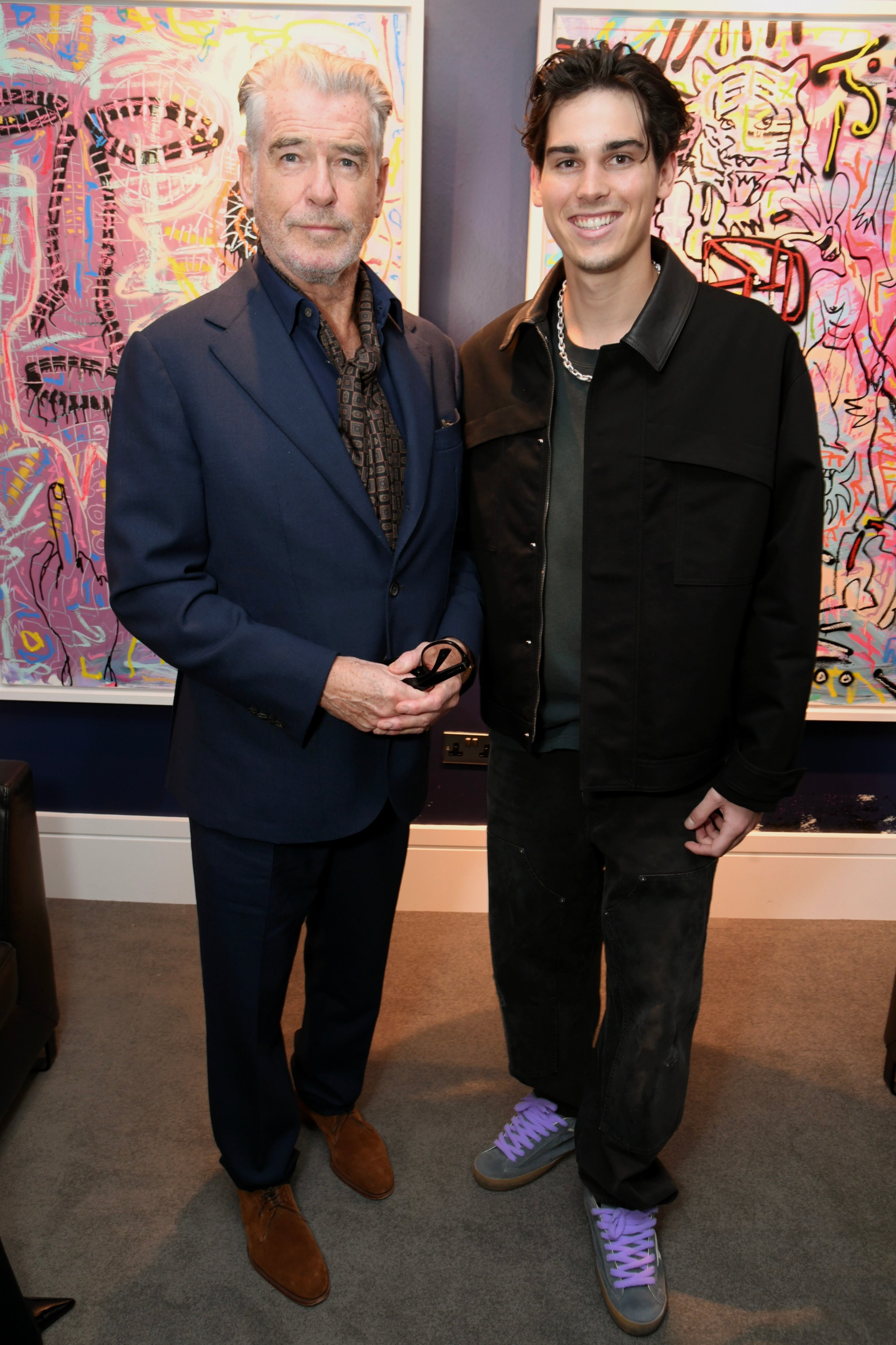 Two men basal   unneurotic  successful  beforehand   of vibrant art. The near  antheral   wears a suit   with a scarf; the close    antheral   sports a casual overgarment   and jeans