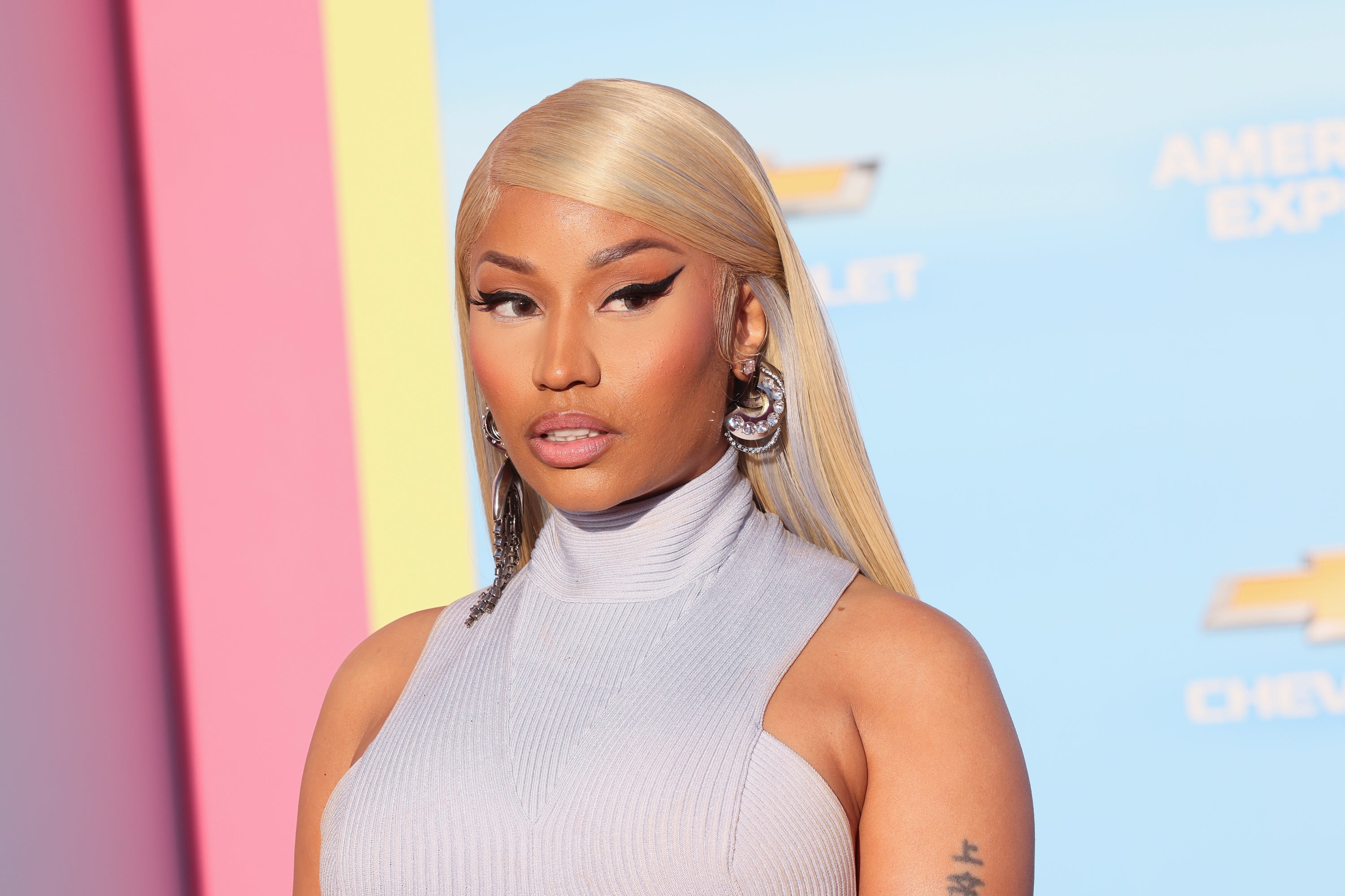 Nicki Minaj successful sleeveless turtleneck apical with agelong consecutive hair, wearing bold constitution and ample earrings, attending a ceremonial event