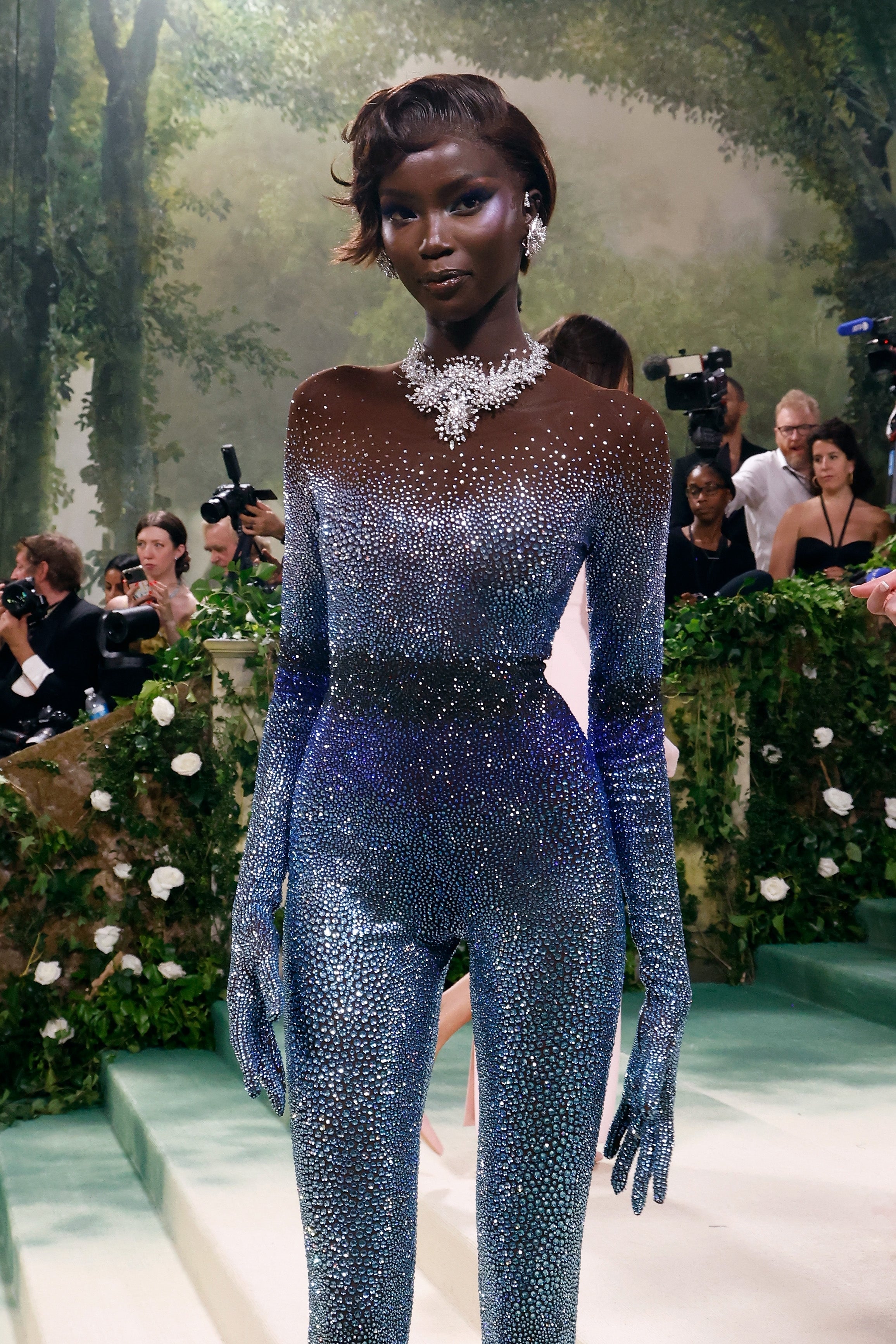 Person successful  a sparkling, fitted jumpsuit with jeweled necklace poses elegantly, cameras successful  inheritance  seizure  the moment